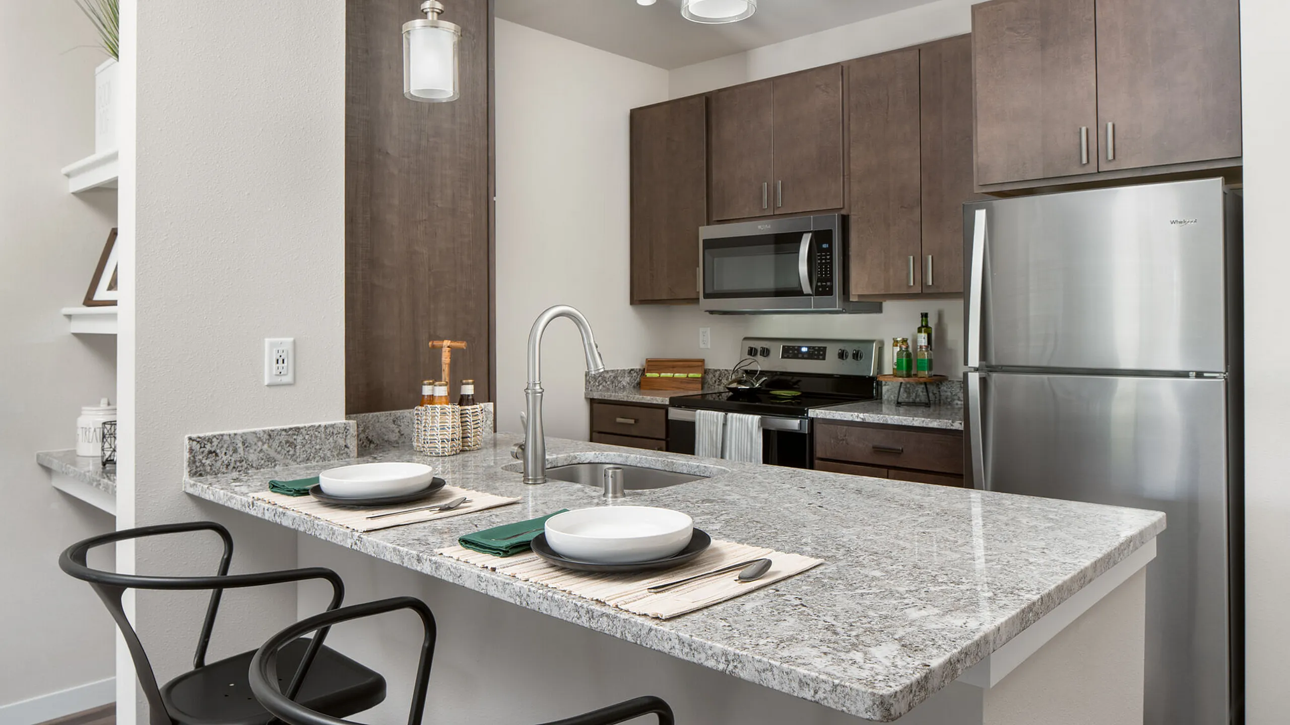 Modern kitchen featuring sleek stainless steel appliances, elegant granite countertops, and a cozy breakfast bar with stylish seating.