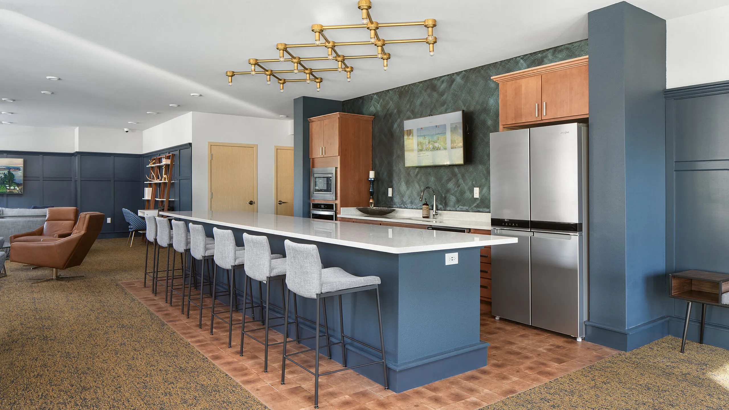 Modern kitchen and living area with sleek stainless steel appliances, elegant lighting, and a spacious island with bar seating.