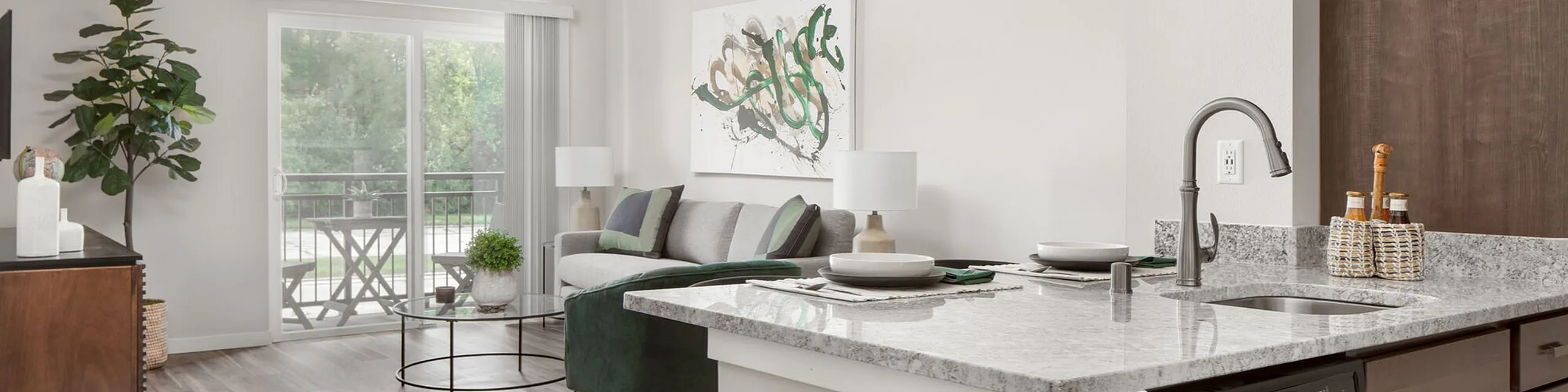 Modern open-concept living space with a stylish kitchen, cozy seating area, and a sunlit balcony view.