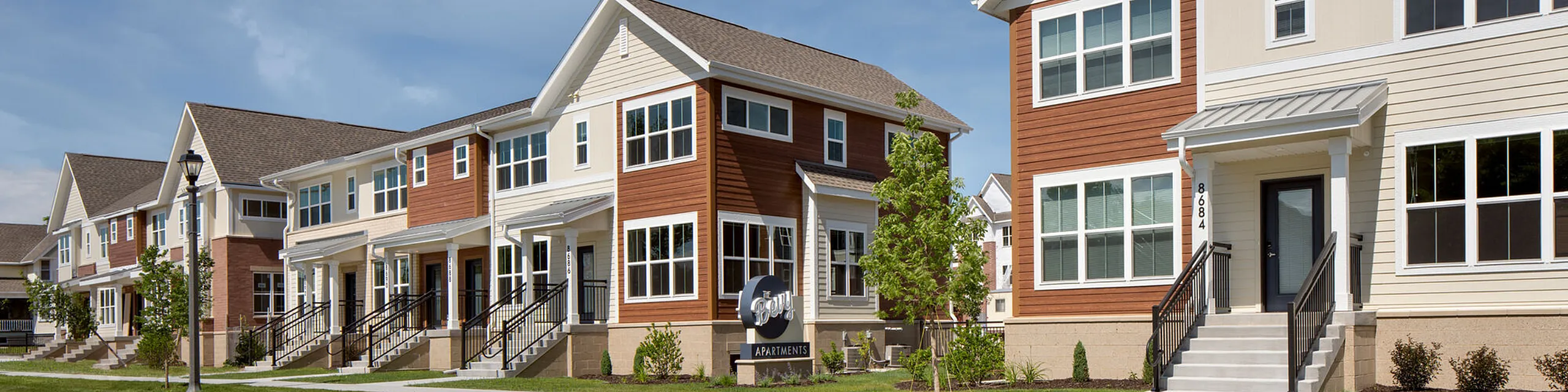 Charming row of modern townhouses with large windows, inviting porches, and lush landscaping.