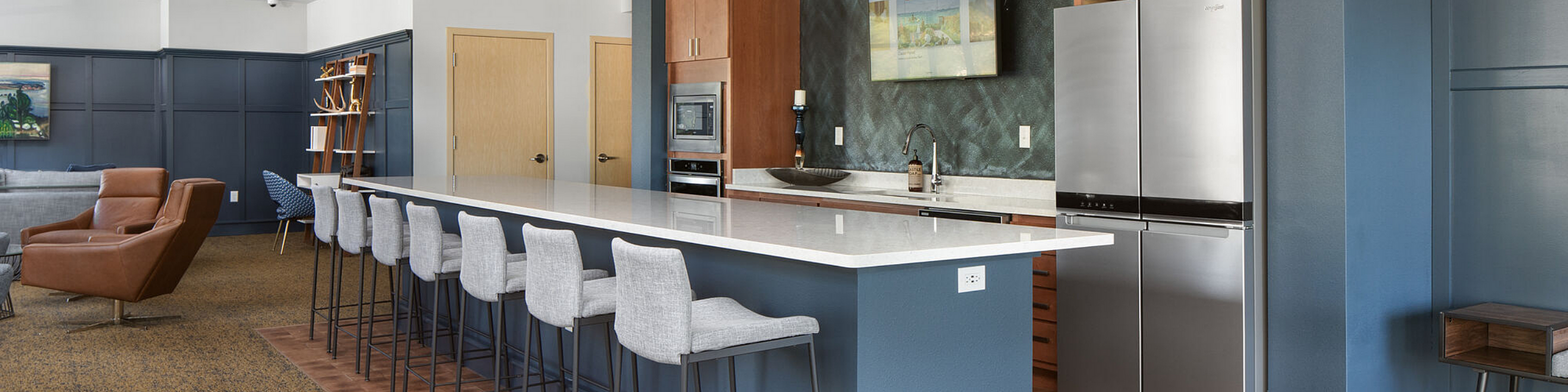 Modern open-concept kitchen with sleek countertops, stainless steel appliances, and stylish bar seating. Cozy lounge area with contemporary furniture and a chic wall design.