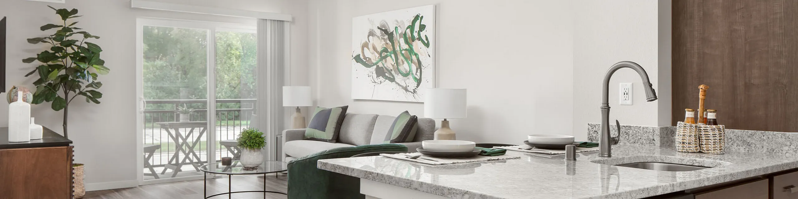 Contemporary open living area in a modern apartment with stylish decor, sleek kitchen island, cozy seating, and abundant natural light from large balcony doors.