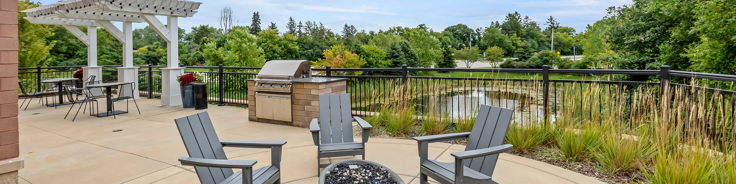 Charming outdoor patio with cozy seating, a modern grill, and scenic nature views surrounded by lush greenery.
