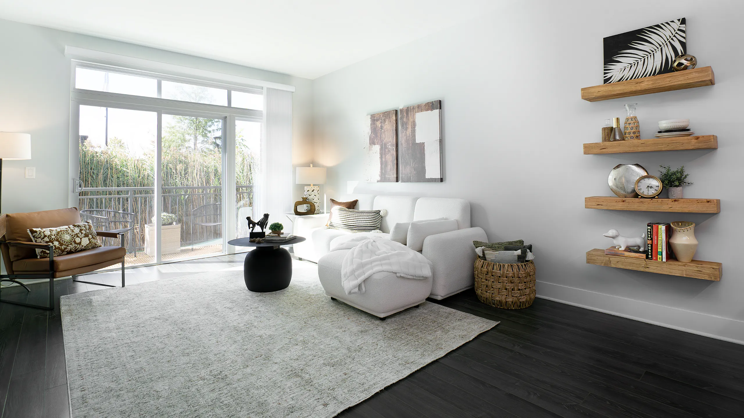 Bright and inviting living room with a cozy white sofa, stylish armchair, modern coffee table, and decorative wall shelves, opening to a serene balcony view.