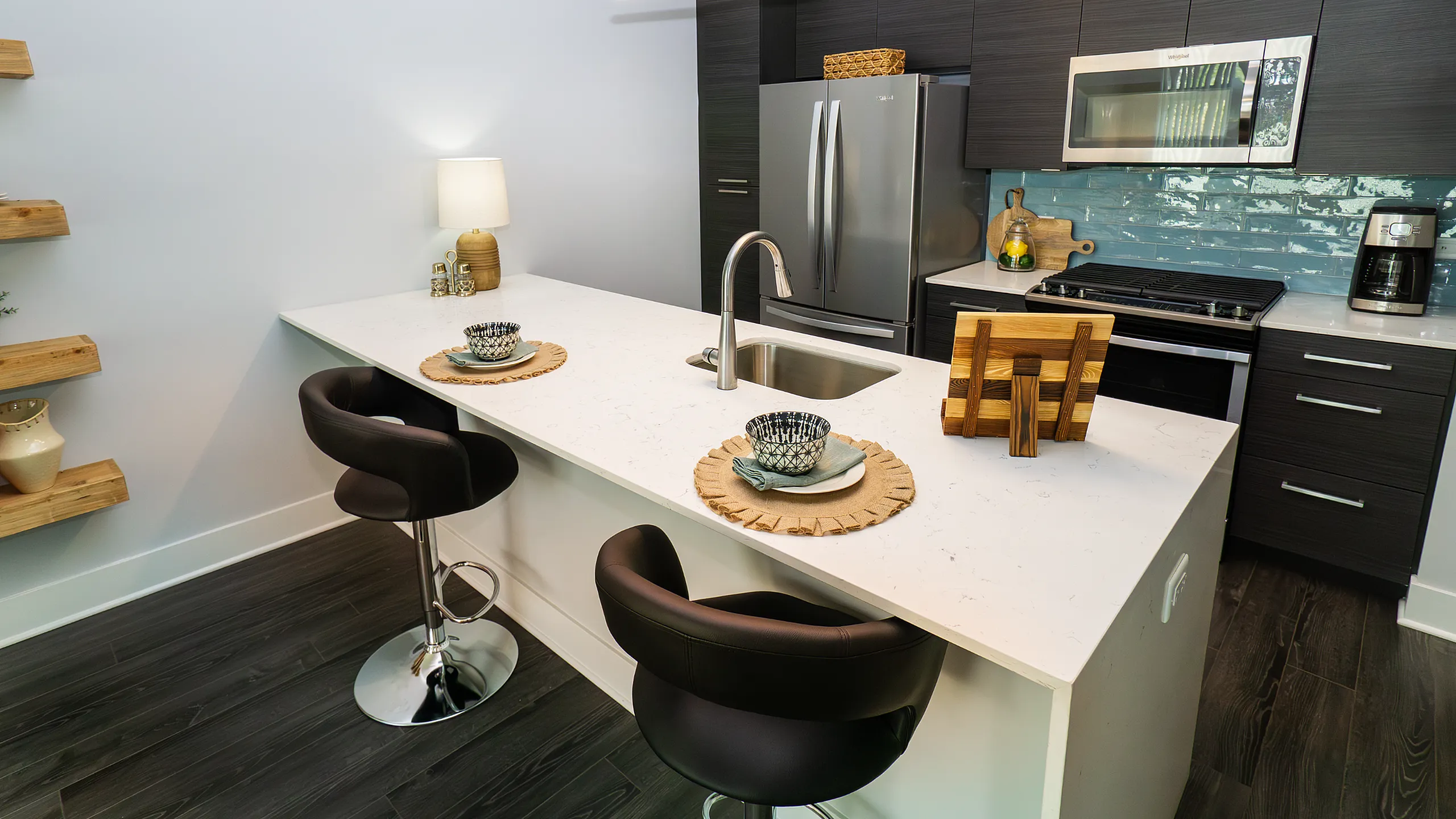 Elegant modern kitchen with sleek dark cabinetry, stainless steel appliances, and a chic white island with stylish seating.