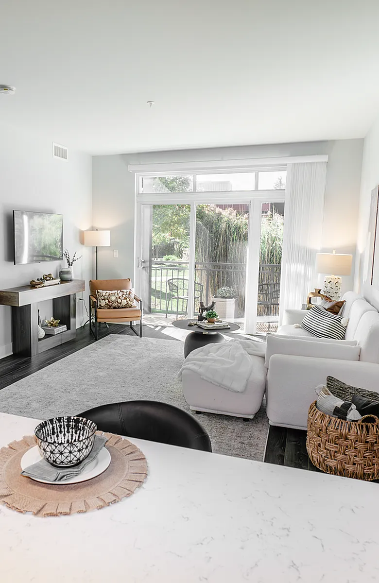 Bright and airy living room with elegant decor, large windows leading to a garden view, and modern furnishing for a cozy ambiance.