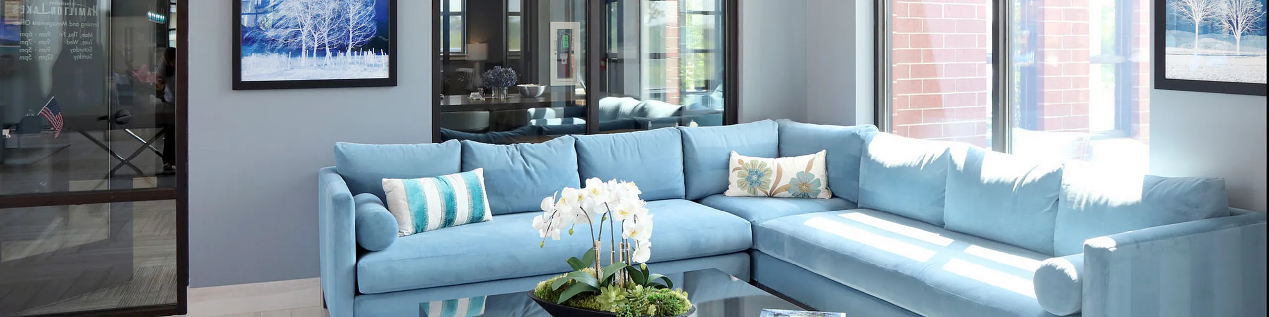 Bright and inviting living room with a modern blue sectional sofa, elegant decor, and large windows allowing natural light.