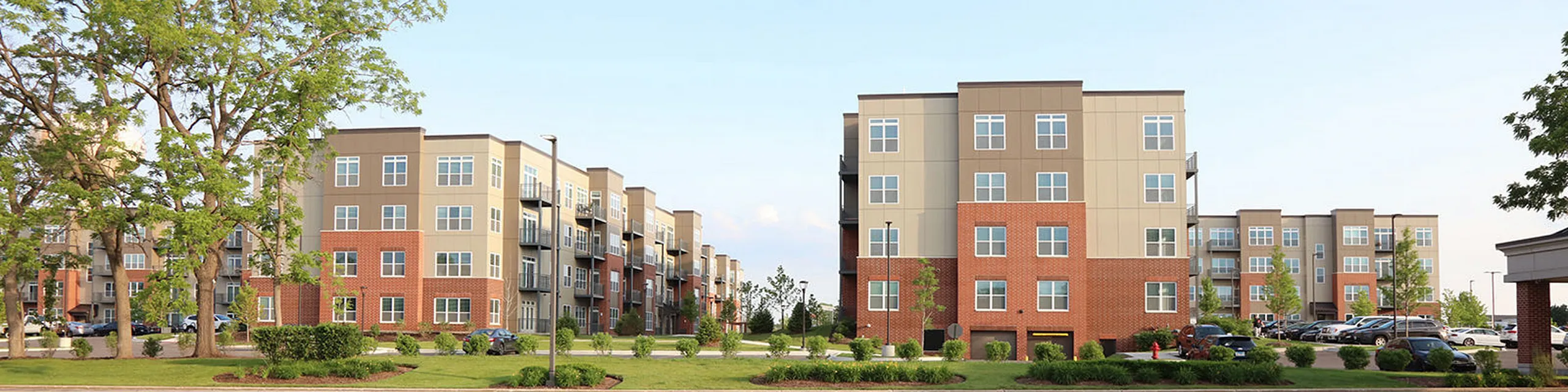 Modern apartment complex featuring elegant architecture, spacious balconies, and lush landscaping.