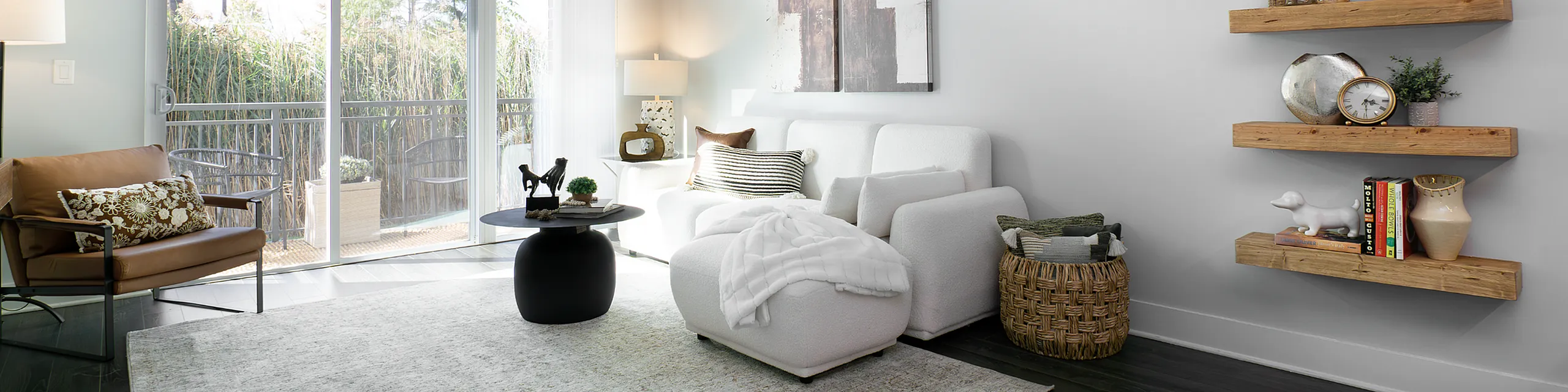 Chic living room with modern decor, featuring a cozy white couch, elegant wooden shelves with stylish accents, and a balcony view inviting natural light.