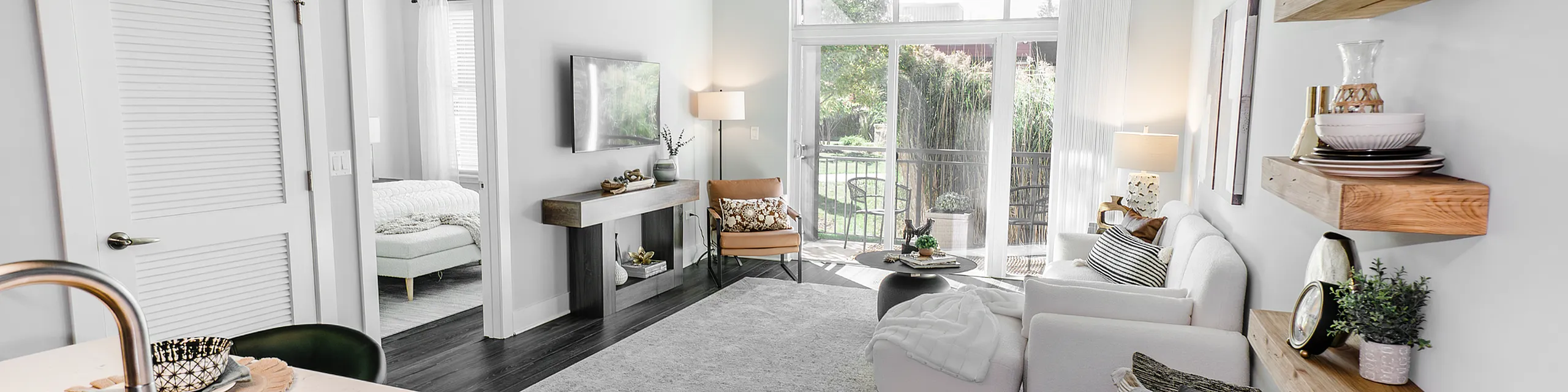 Bright and modern living room with large windows, elegant decor, and a cozy seating area overlooking lush greenery.