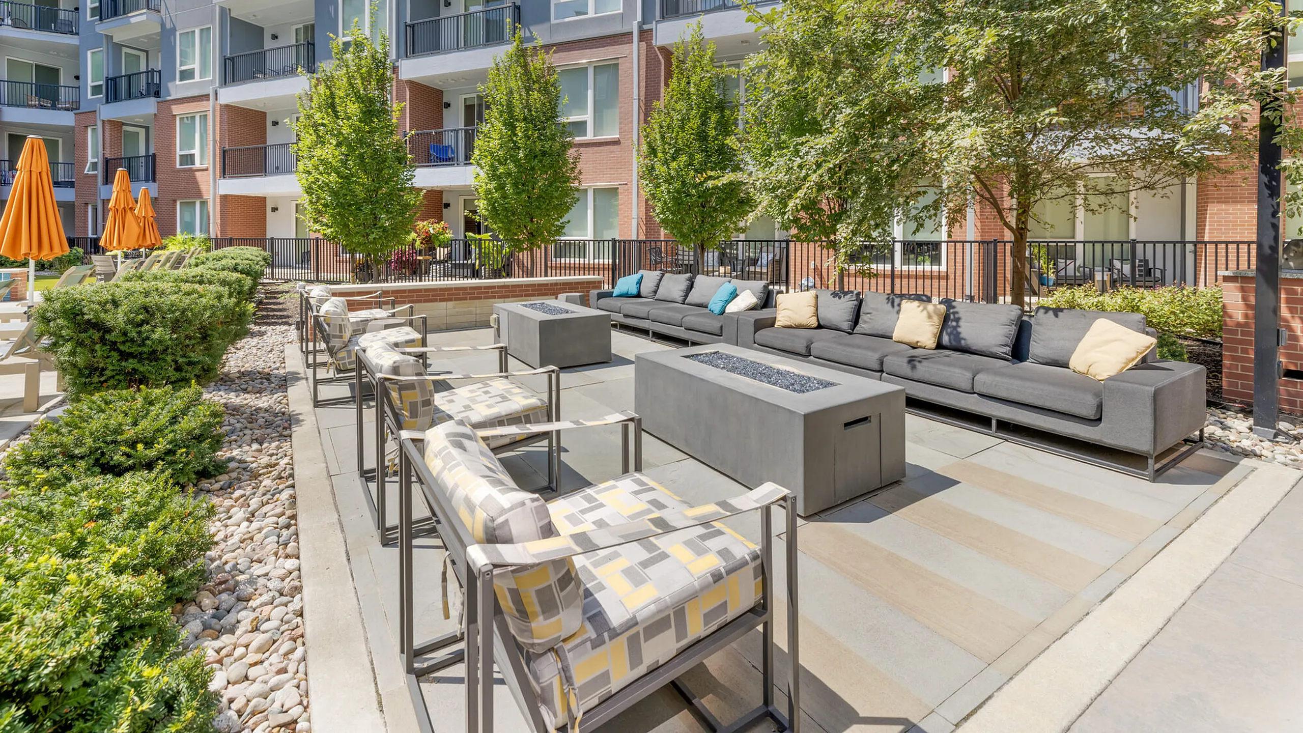Modern outdoor lounge area featuring sleek seating, trendy fire pits, and vibrant umbrellas, perfect for relaxation and socializing.