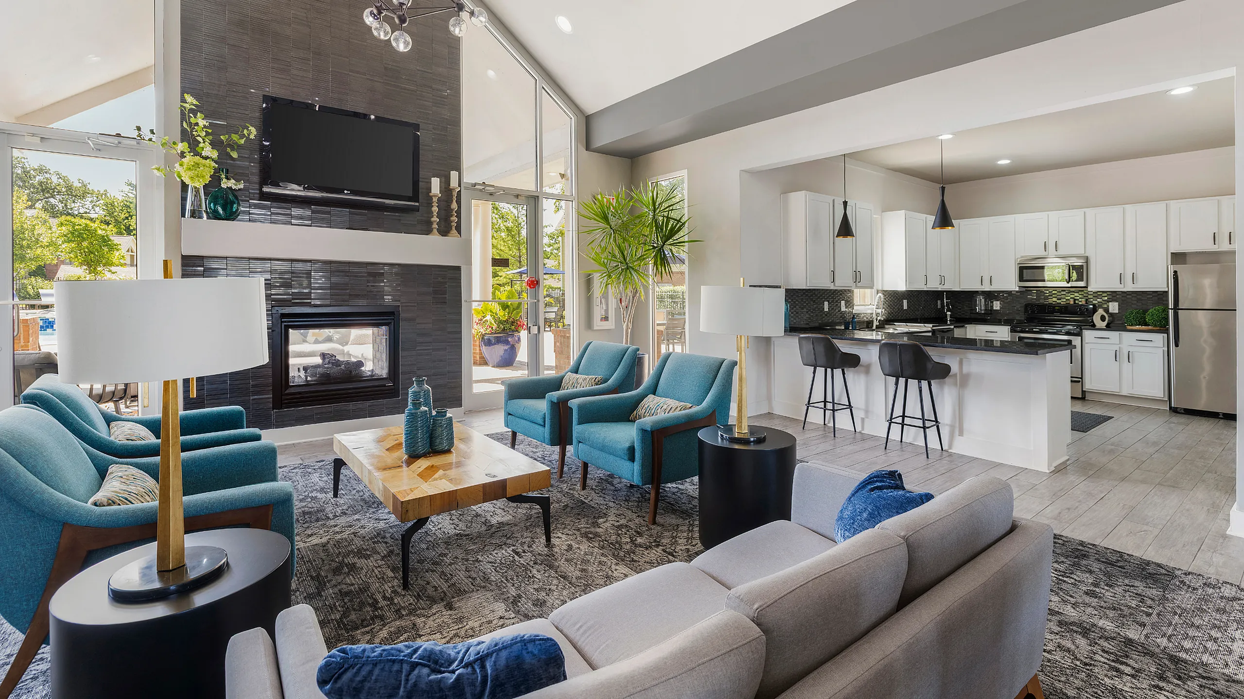 Modern open-plan living area featuring a cozy fireplace, elegant seating, and a sleek kitchen with a breakfast bar and vibrant decor.