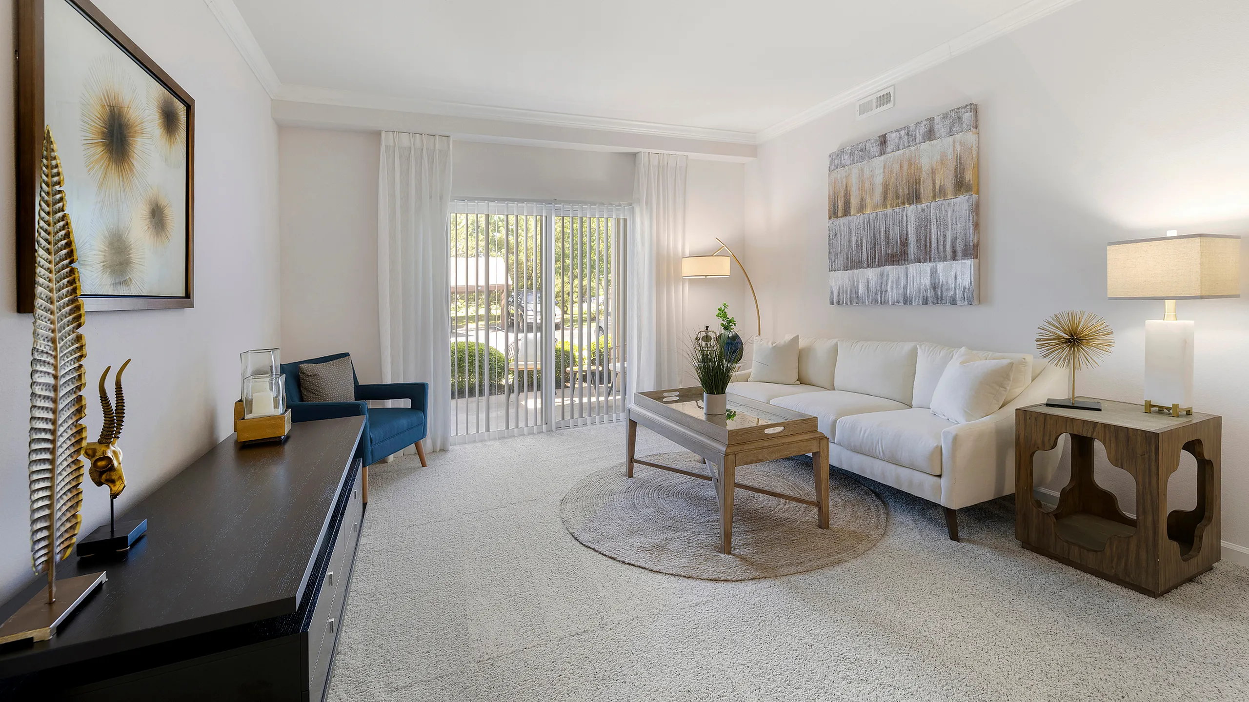 Bright and inviting living room with cozy white sofa, modern artwork, and stylish decor, featuring large sliding doors opening to a vibrant garden view.