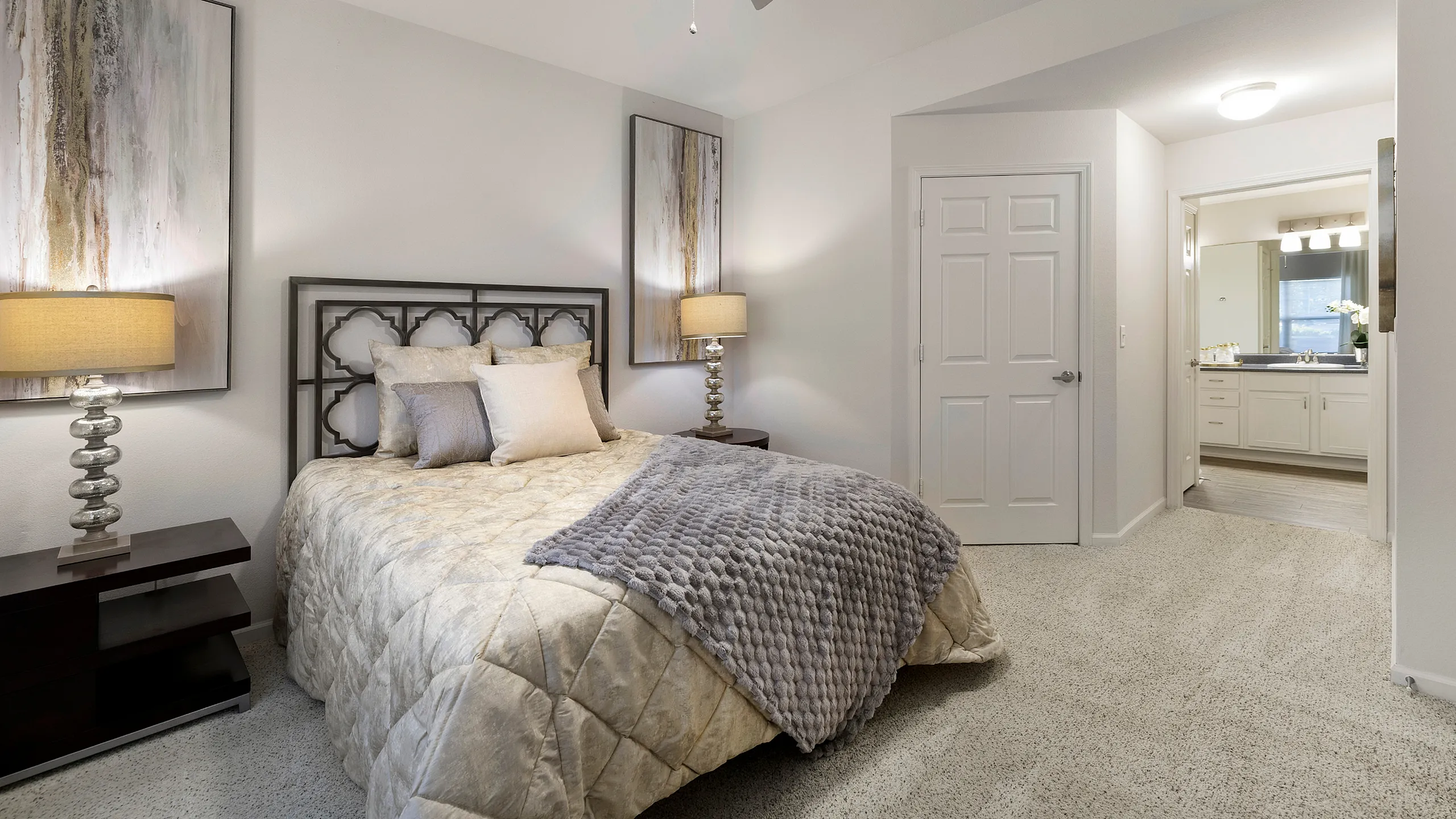 Inviting bedroom with elegant decor, plush bedding, ambient lighting, and ensuite bathroom access, perfect for relaxation and comfort.