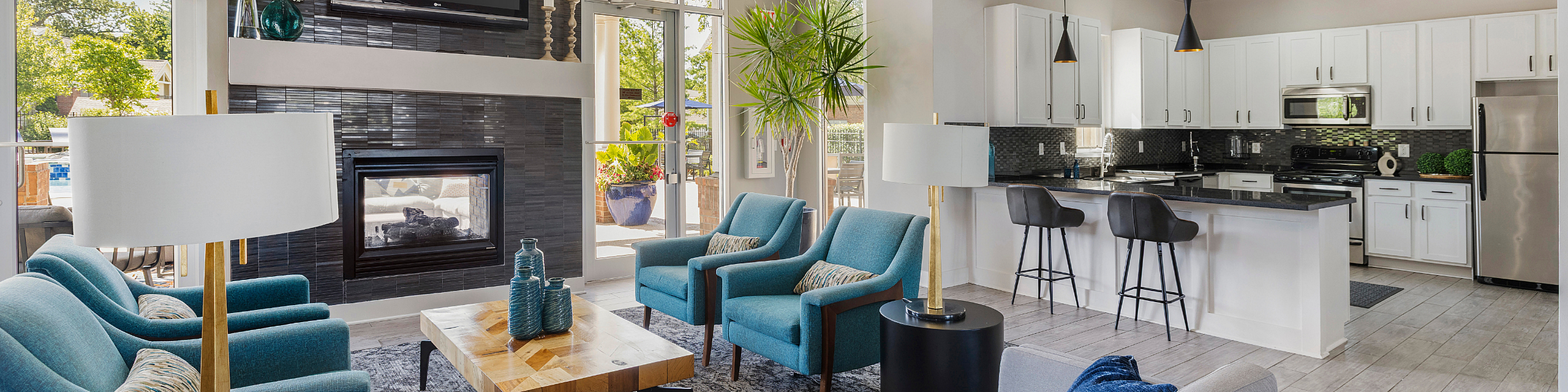 Bright and modern living room with sleek kitchen, stylish furniture, and large windows offering scenic outdoor views.