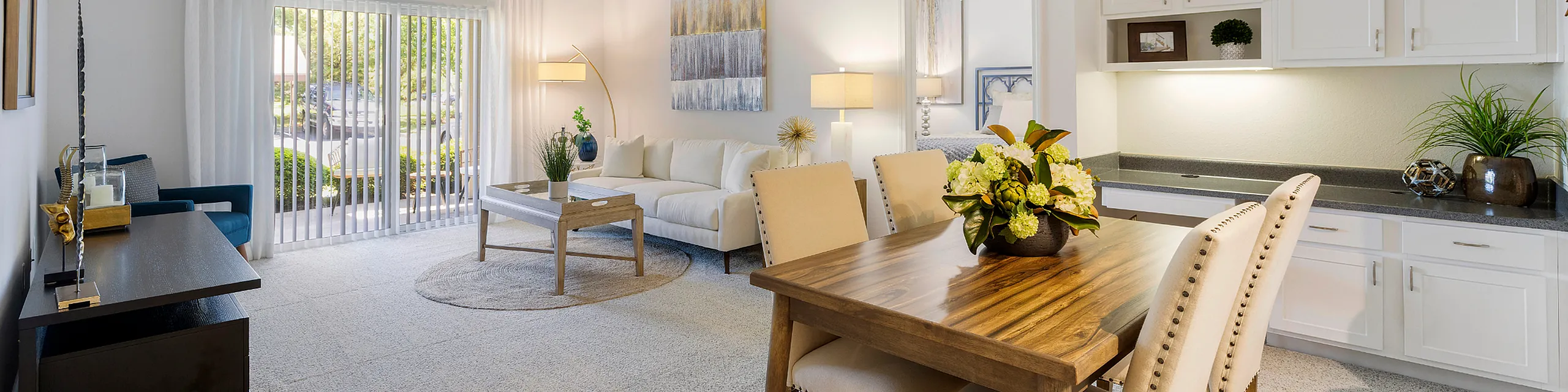 Elegant living and dining area with modern decor, featuring a plush sofa, stylish wooden dining table, and natural light streaming through large windows.