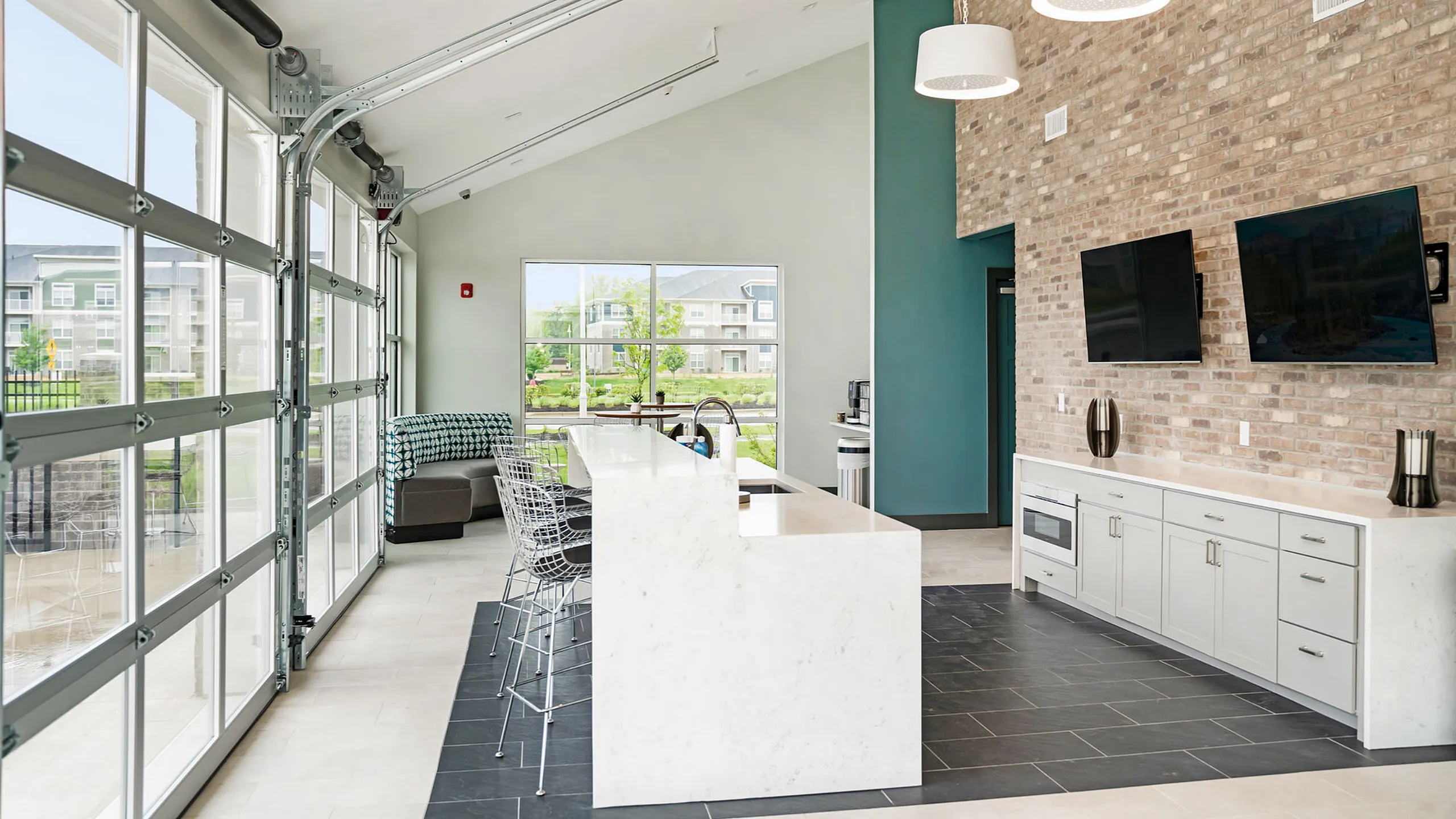 Modern open-concept apartment featuring a sleek kitchen island, large windows, and contemporary decor with a view of lush greenery.
