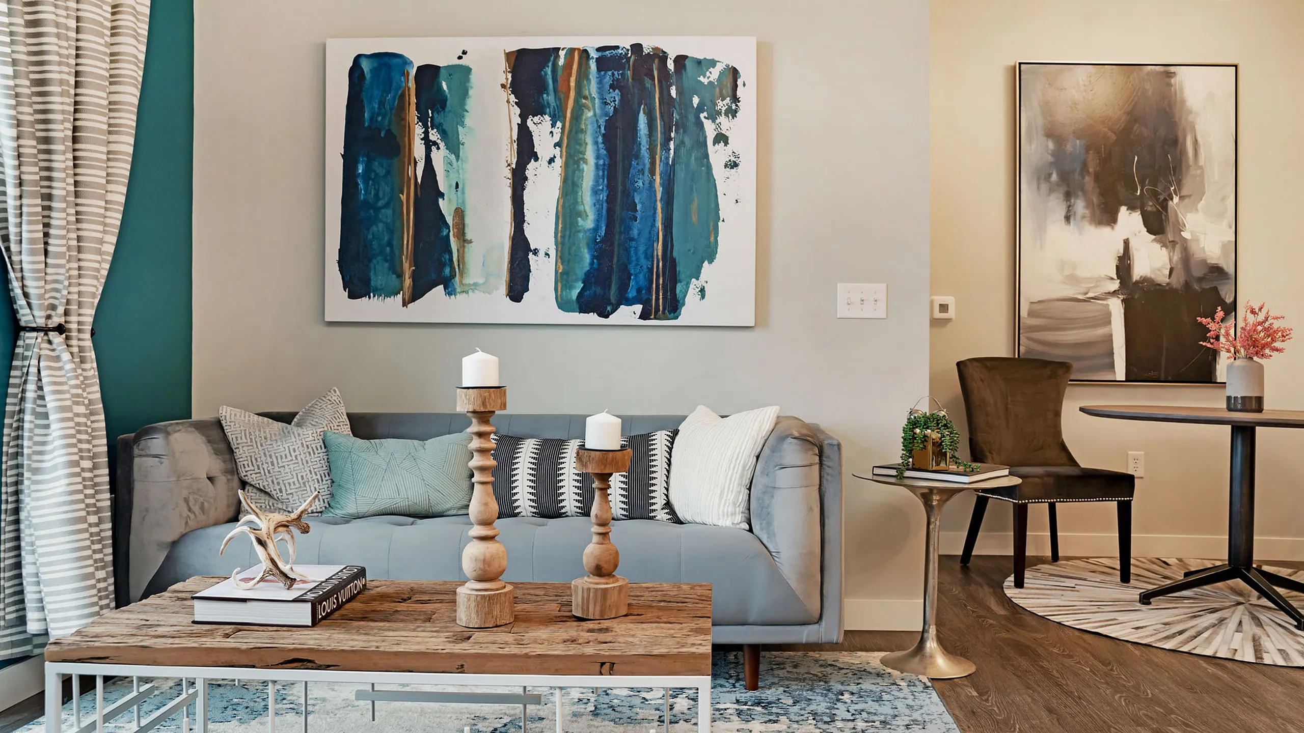Chic living room with modern art, elegant gray sofa, wood-accented decor, and stylish furnishings creating a cozy ambiance.