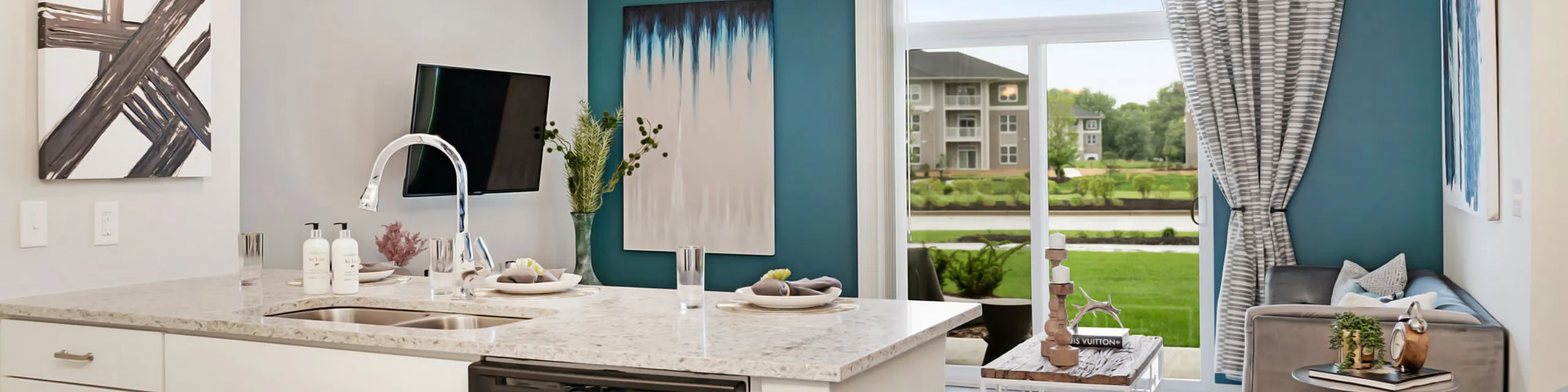 Contemporary kitchen with sleek design, marble countertops, and vibrant living area with garden views through large windows.