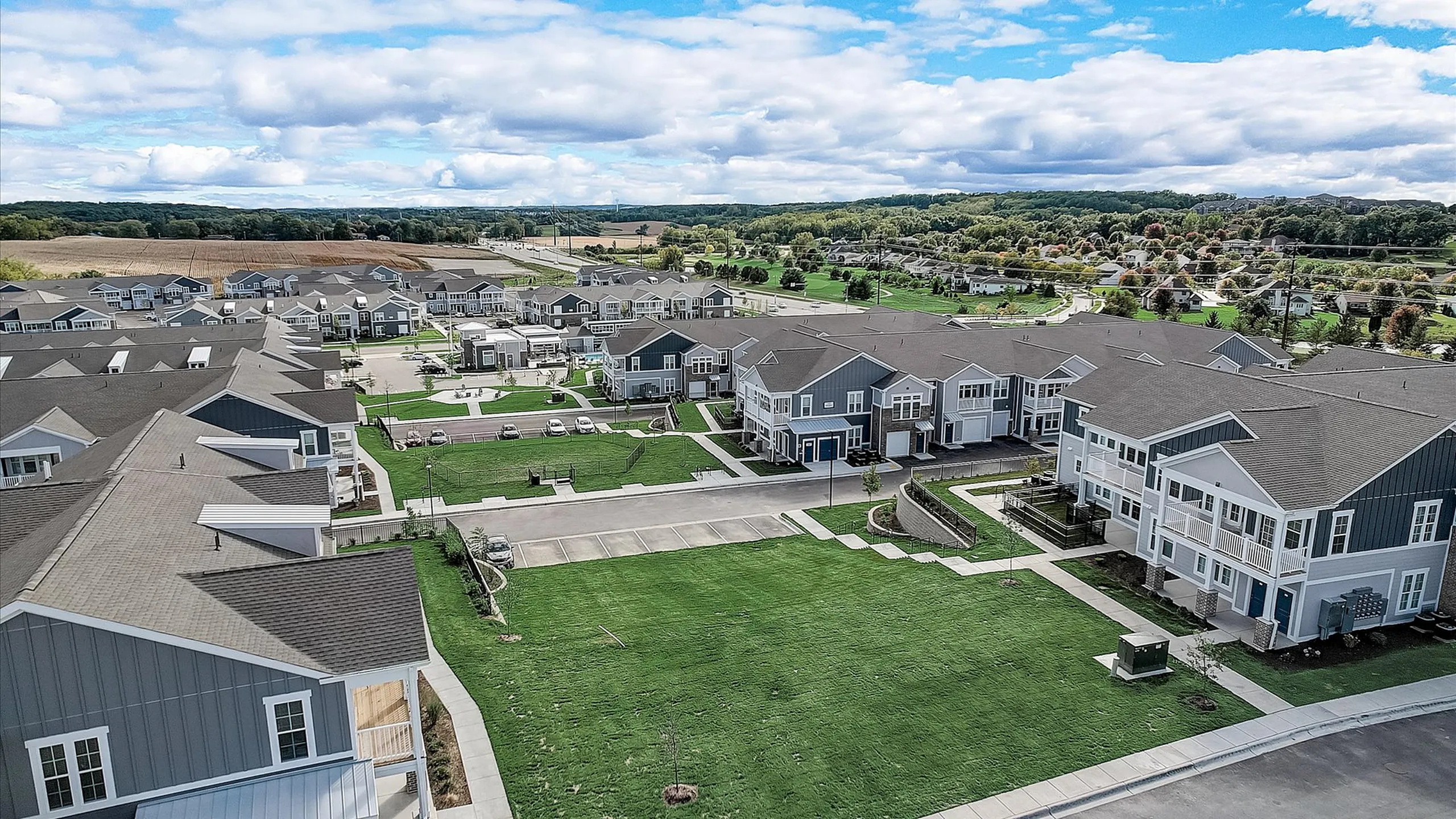 Charming suburban apartment complex surrounded by lush greenery, featuring modern architecture and ample parking spaces.