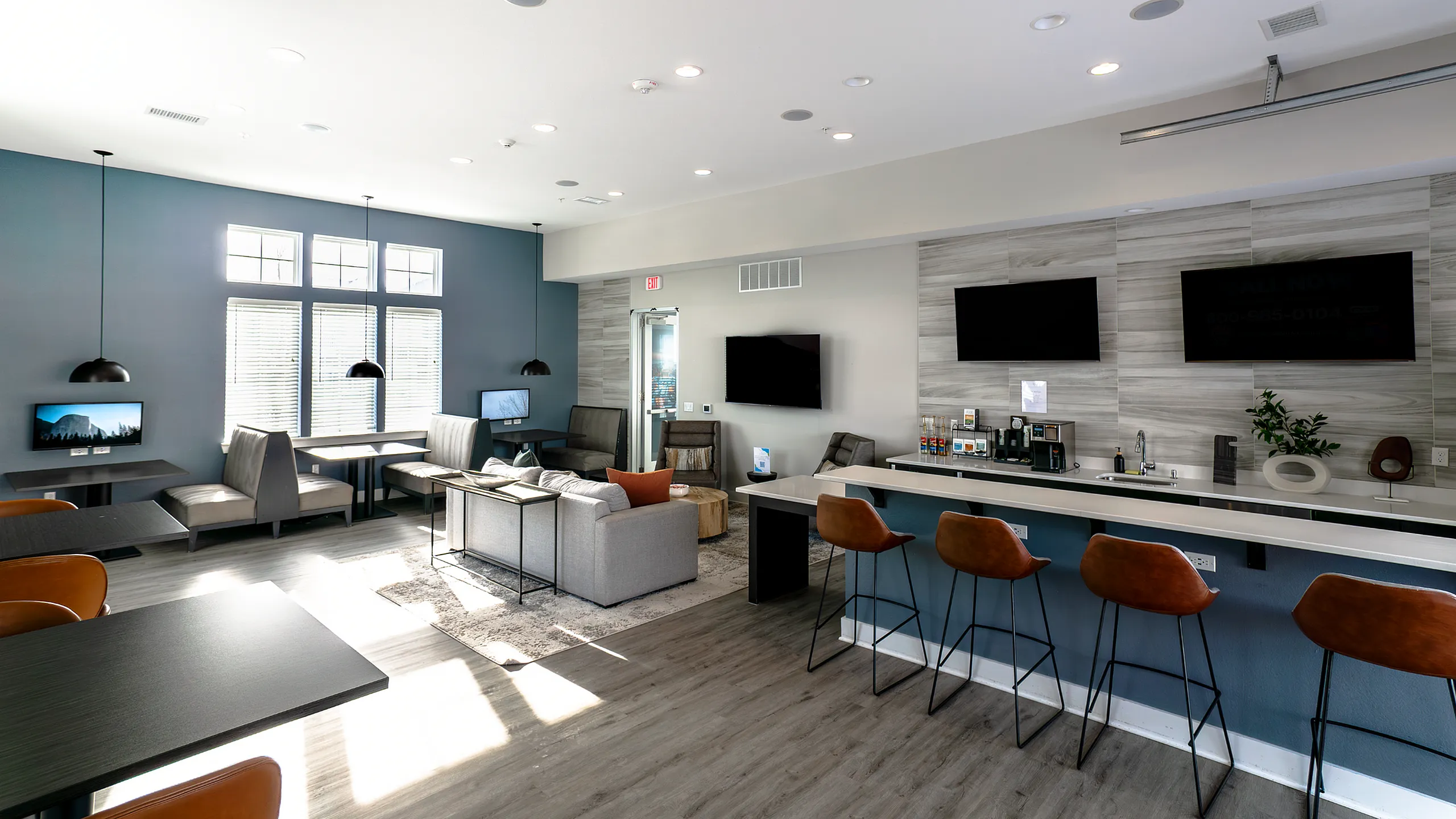 Modern communal space with stylish seating, a sleek bar area, and multiple flat-screen TVs, perfect for socializing and relaxation.