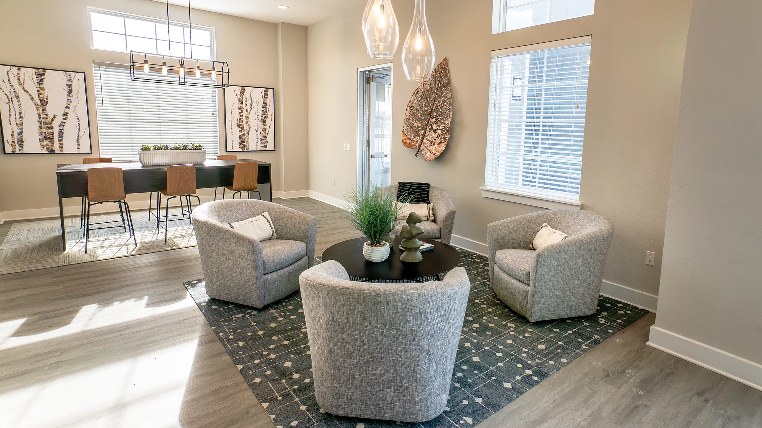Modern living space with stylish decor, featuring a cozy seating area with plush armchairs and a chic dining table, accented by natural light and elegant artwork.