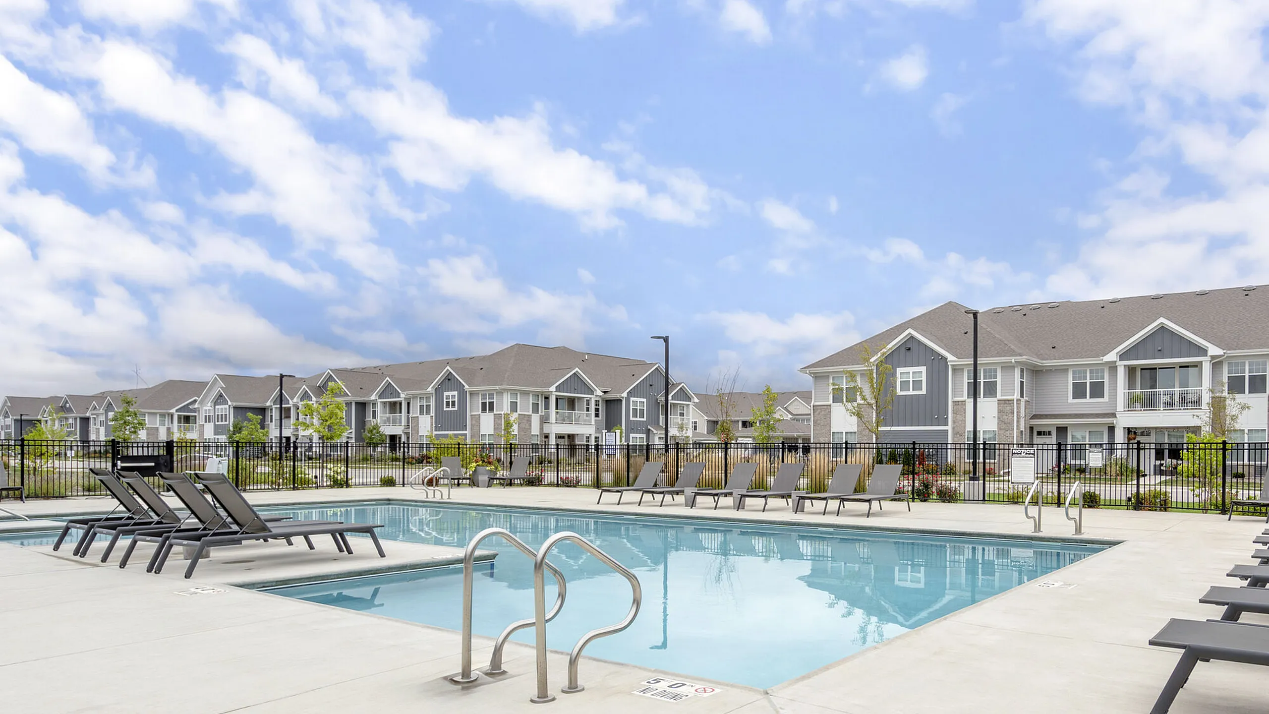 Charming apartment complex with modern architecture and a sparkling pool, set under a clear blue sky.