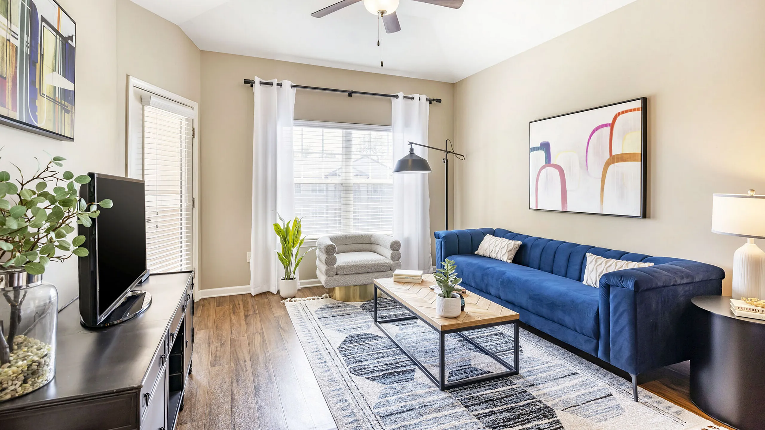 Inviting living room with a modern blue sofa, chic decor, and ample natural light streaming through large windows.