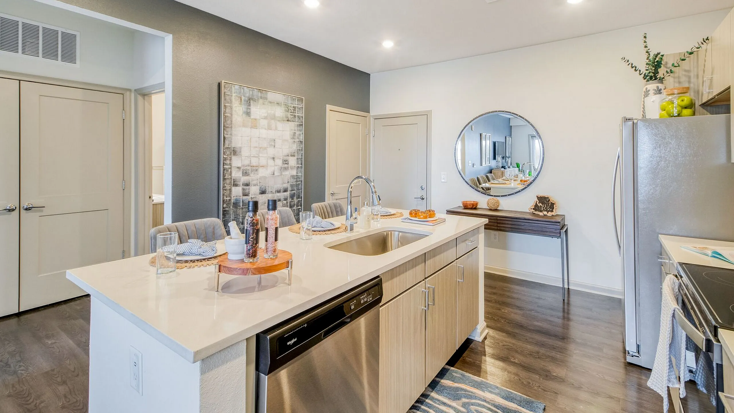 Modern apartment kitchen with sleek countertops, stylish lighting, and stainless steel appliances, blending elegance and functionality.