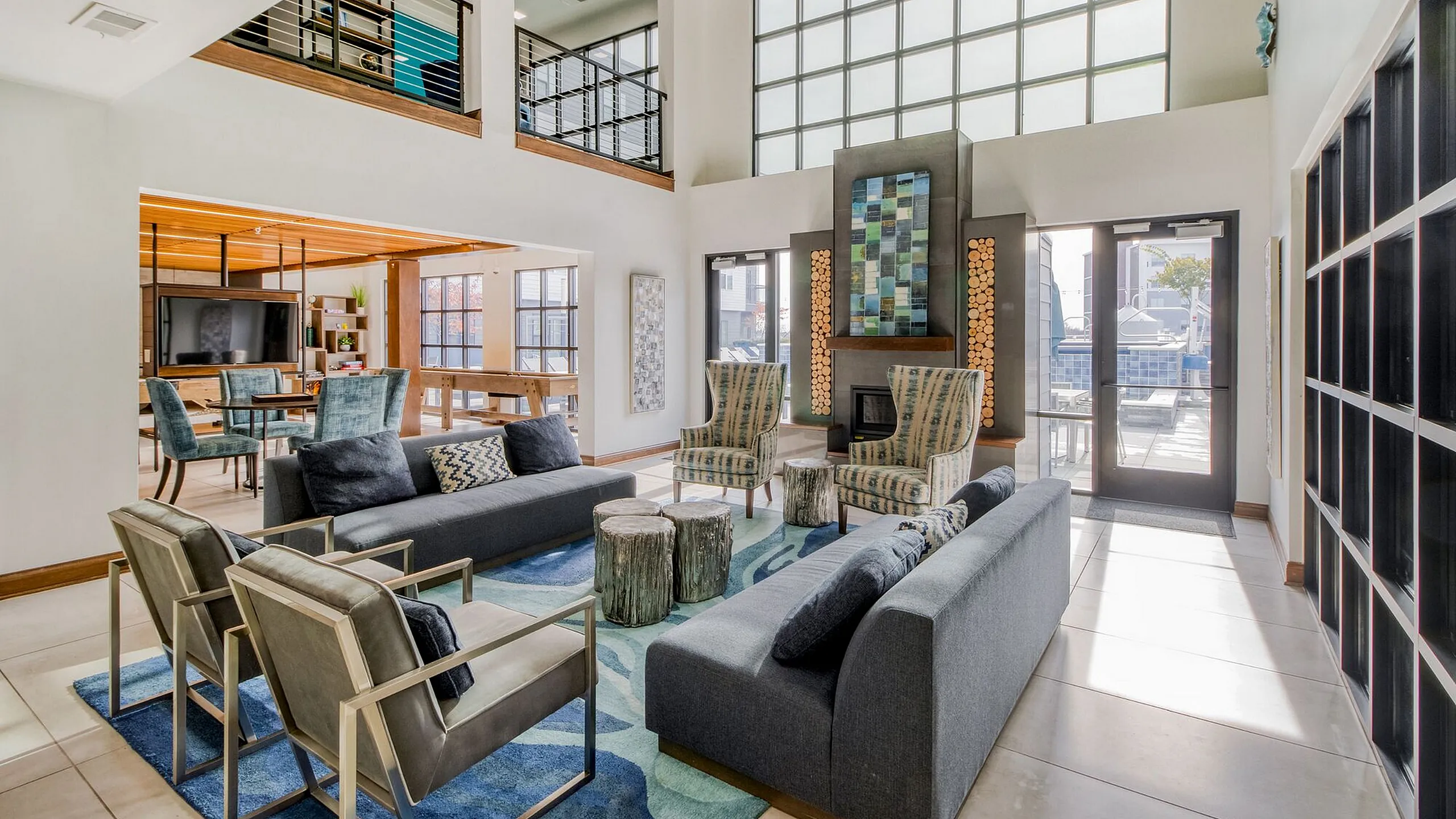 Elegant living area with high ceilings, modern furniture, and vibrant artwork, featuring a cozy fireplace and ample natural light.