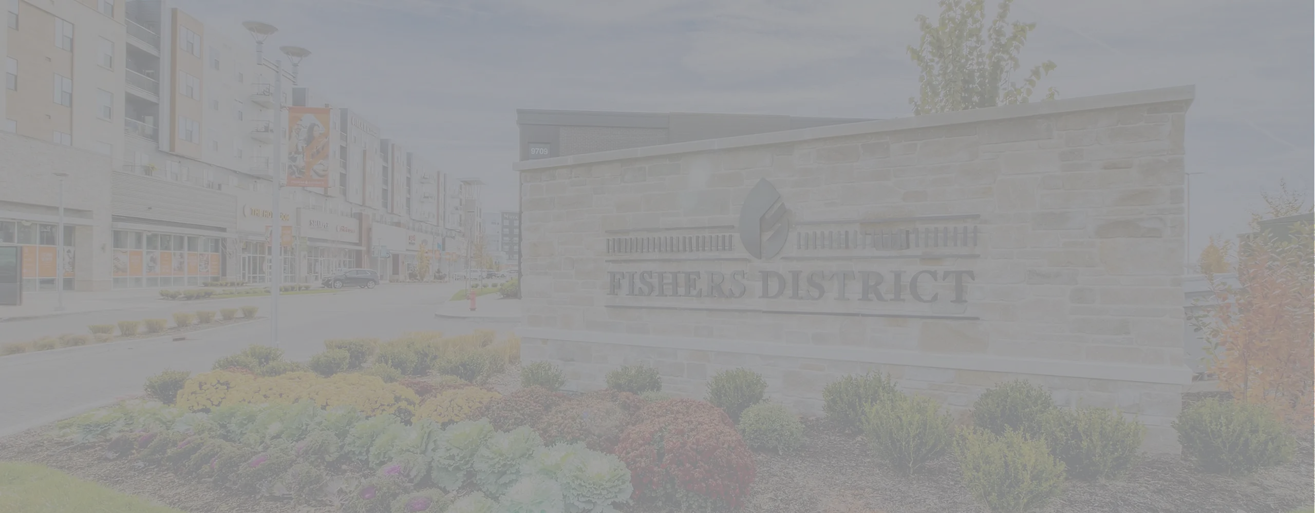 Vibrant Fishers District entrance with modern architecture and lush landscaping, showcasing a thriving community atmosphere.