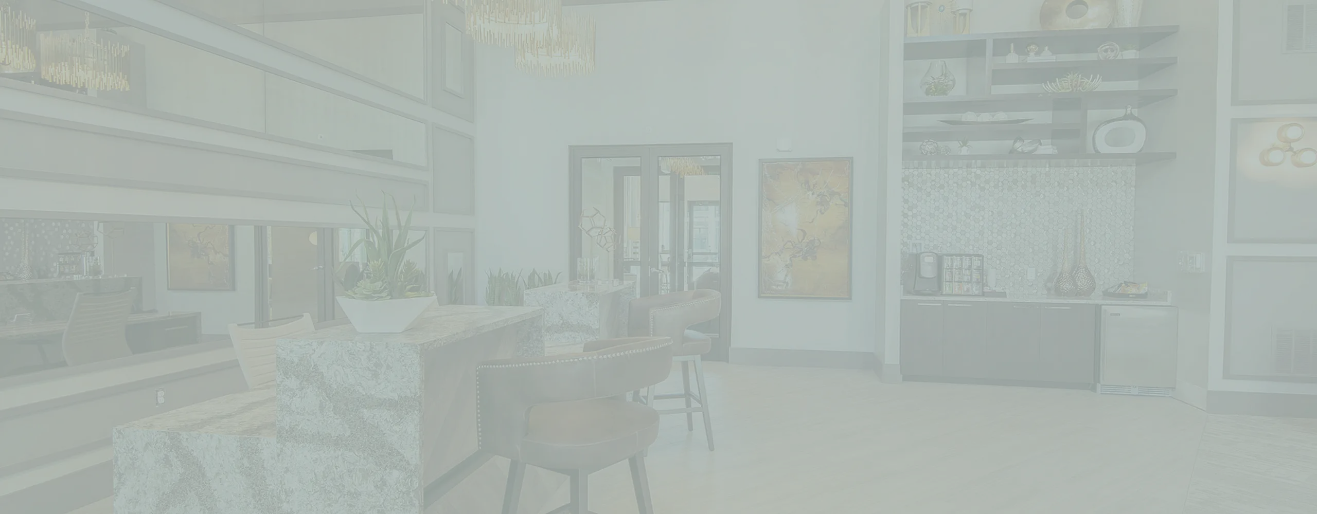 Elegant apartment lobby featuring modern decor with chic lighting, sleek granite counter with stylish bar stools, and a cozy coffee area.