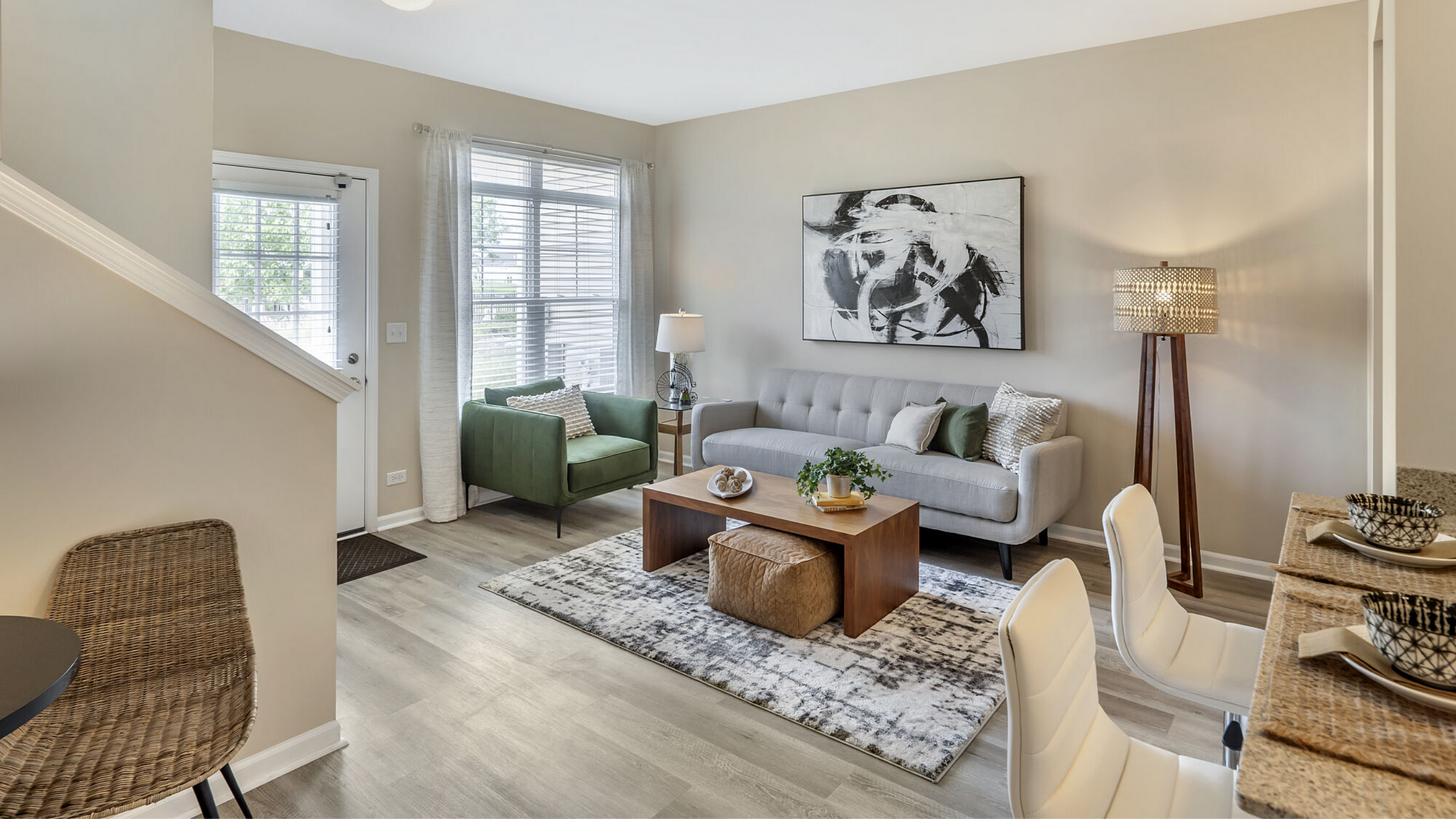 Sophisticated living room with modern decor, featuring a cozy gray sofa, stylish green armchair, and elegant wooden coffee table. The warm lighting and tasteful artwork create a welcoming ambiance.