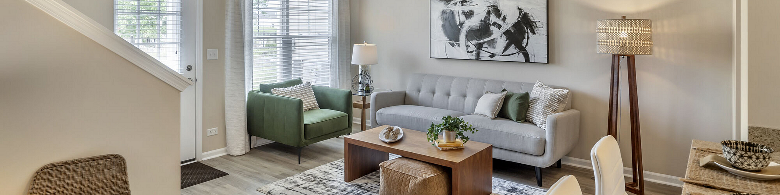 Bright and inviting living room with modern decor featuring a green armchair, sleek gray sofa, abstract art, and stylish floor lamp.