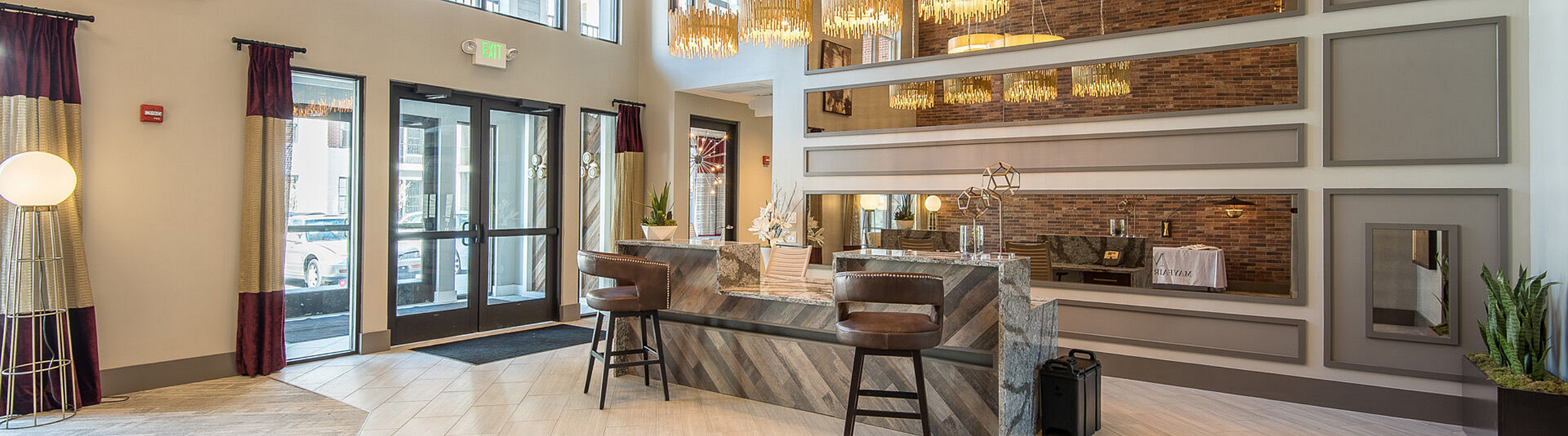 Elegant apartment lobby featuring modern chandelier lighting, stylish bar seating, and sophisticated design elements.