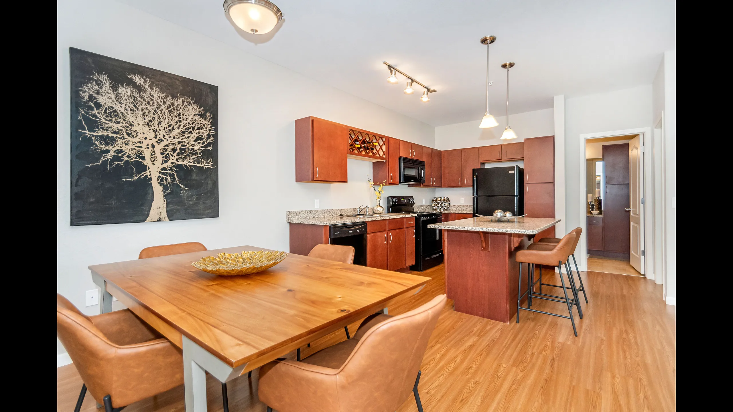 Open-concept kitchen and dining area featuring granite countertops, warm cabinetry, an island and wood-style flooring