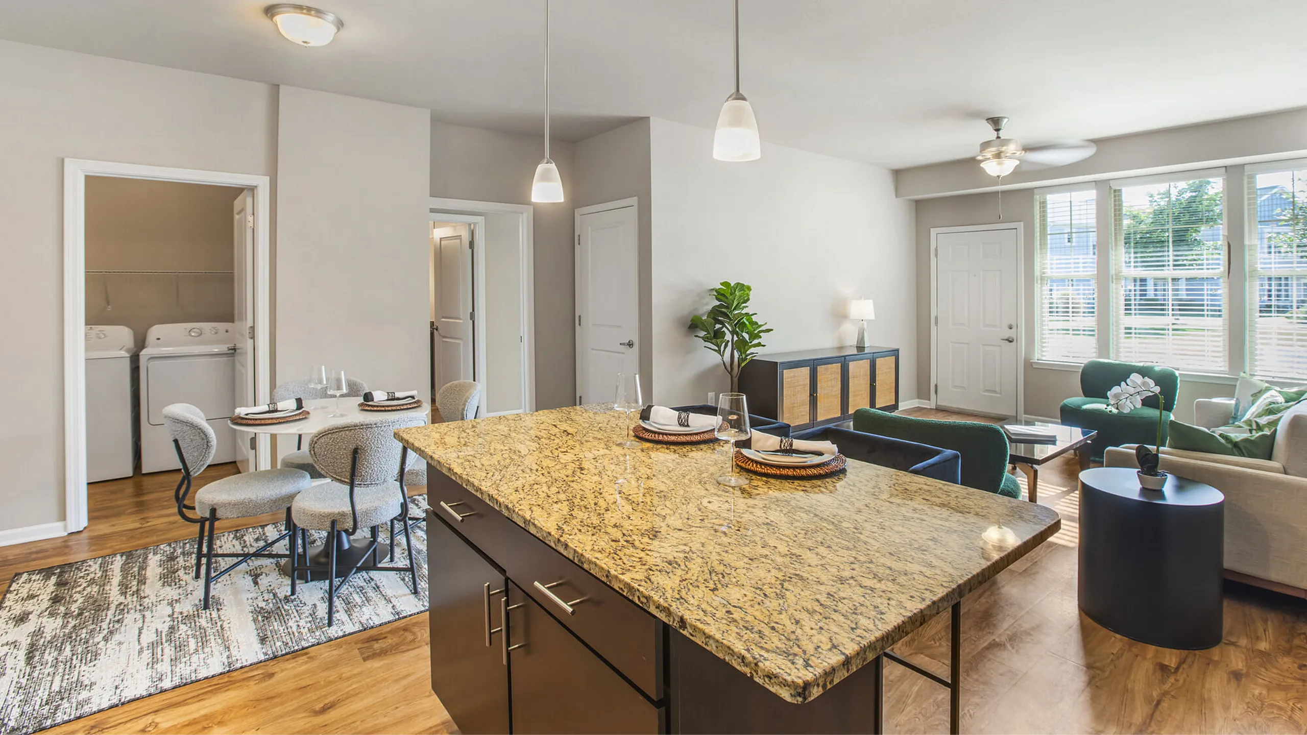 Chic open-plan apartment featuring a modern kitchen with granite countertops, cozy dining area, and sunlit living room with elegant wood flooring.