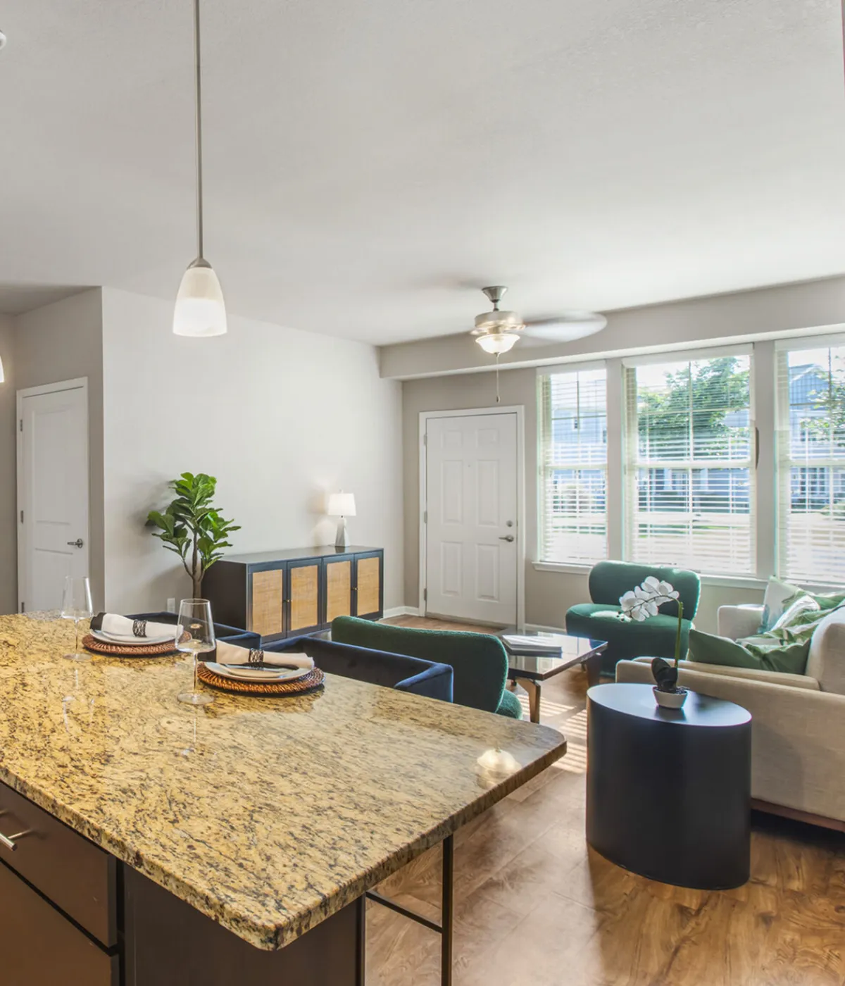 Inviting open-concept living area with modern granite countertop, elegant dining setup, and natural light streaming through large windows.