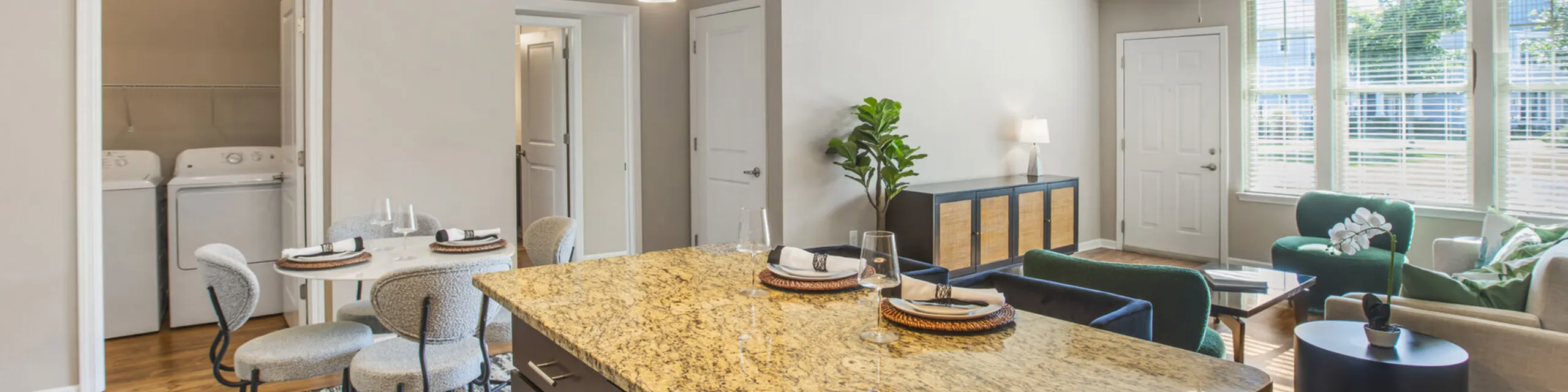 Inviting open-plan apartment with a modern kitchen, elegant dining area, cozy living room, and in-unit laundry for convenience.