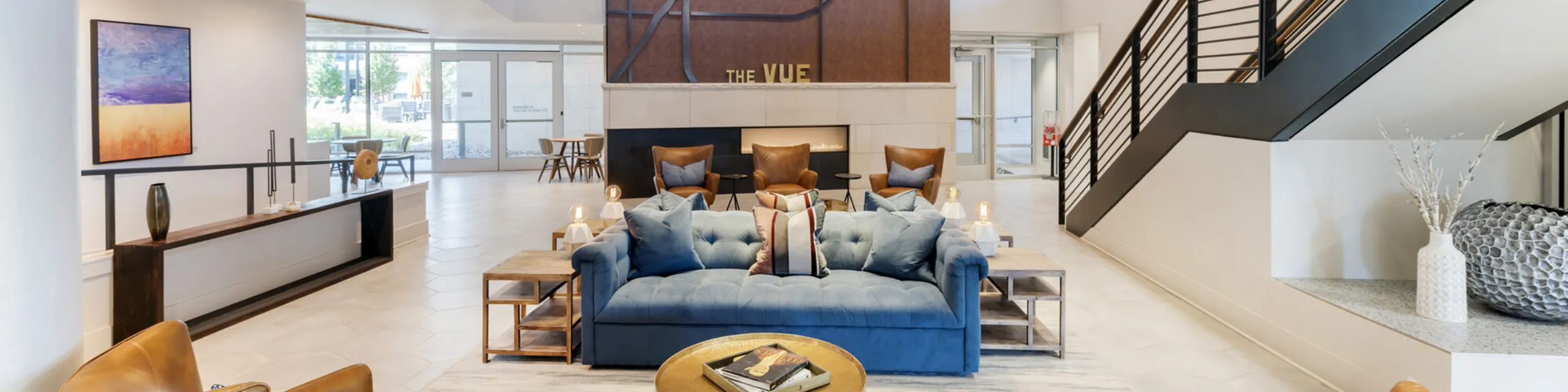 Bright and stylish living room with modern decor, featuring elegant blue seating, lush greenery, and a wall-mounted TV for comfort and elegance.