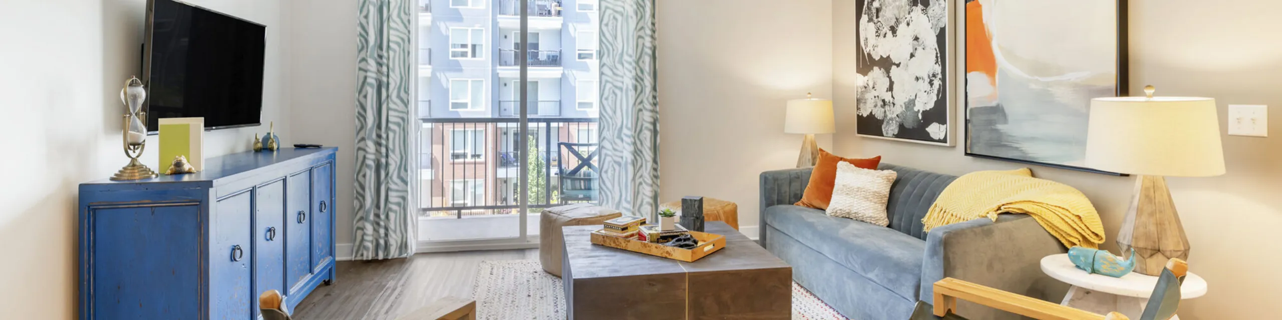 Modern living room with cozy white sofa, stylish coffee table, and elegant shelving, featuring a sunlit balcony view.