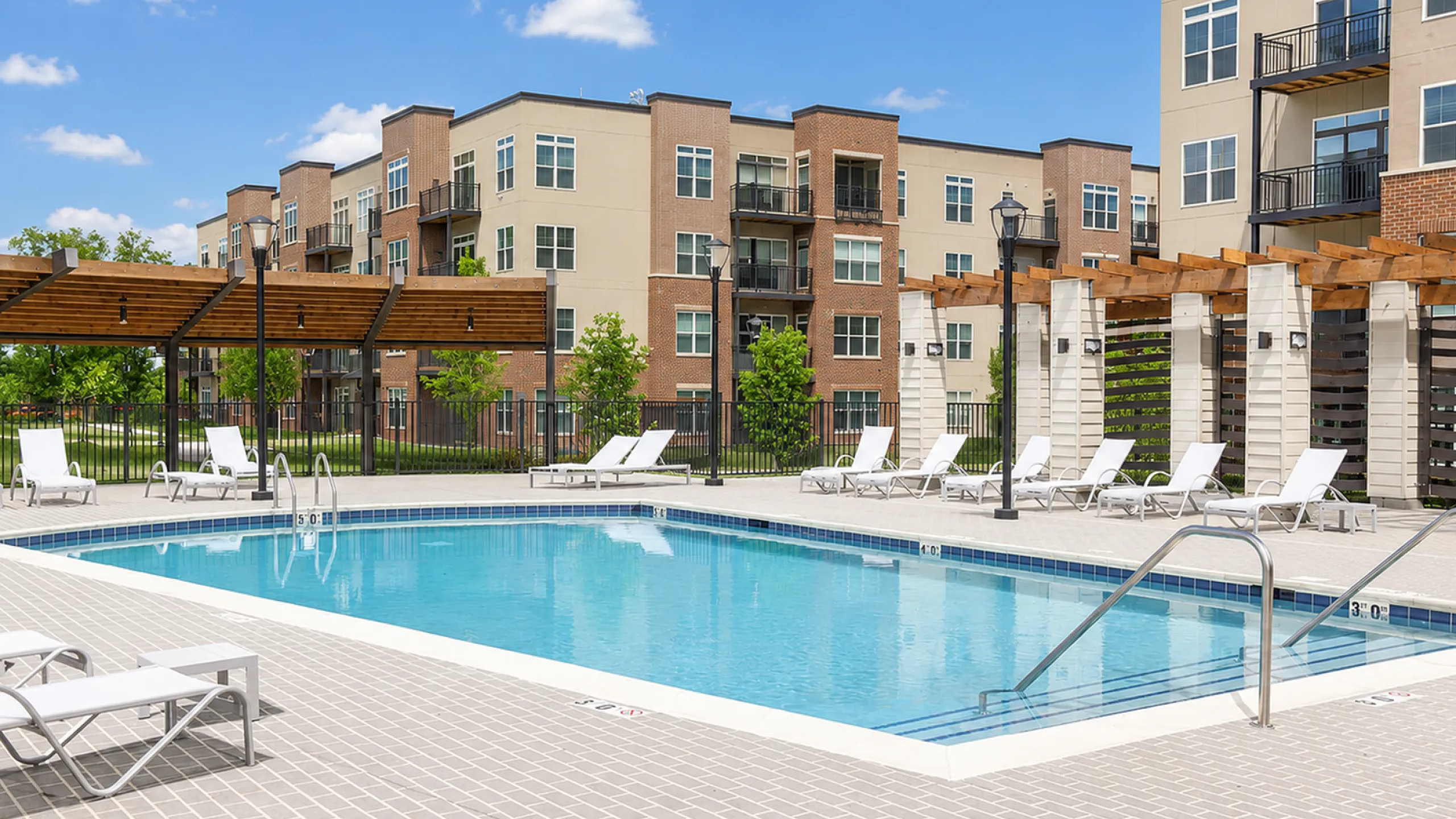 Luxurious outdoor swimming pool area with elegant lounge chairs and stylish pergolas, beautifully illuminated for nighttime relaxation.