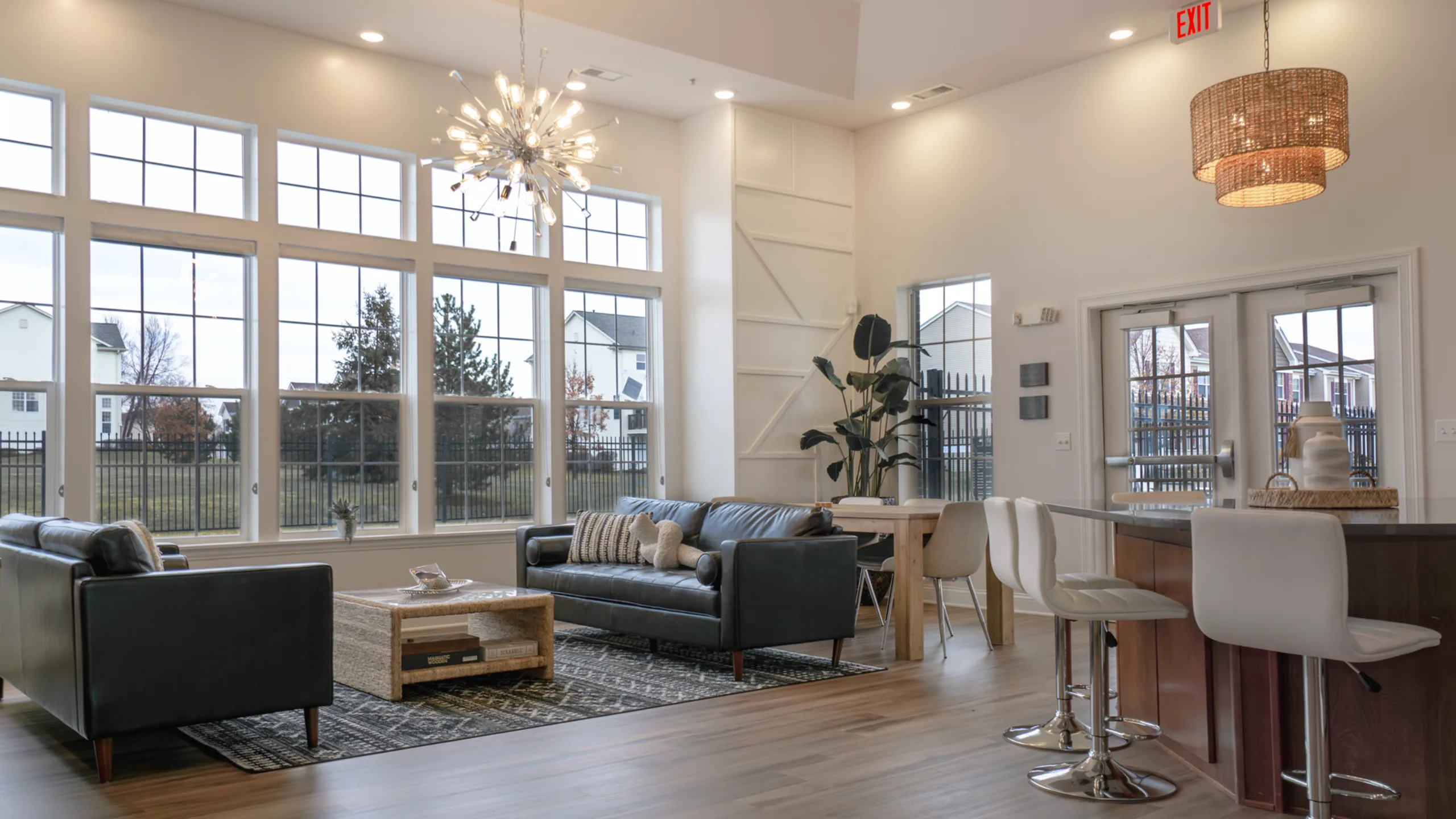Modern apartment interior with open kitchen, cozy breakfast bar, and elegant dining area beside carpeted stairs.