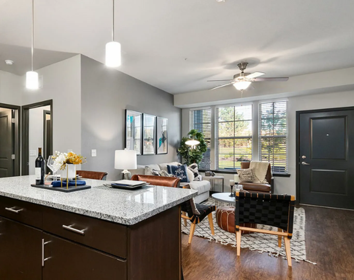 Modern open-concept living room with stylish decor, featuring a sleek kitchen, comfortable seating, and chic artwork.