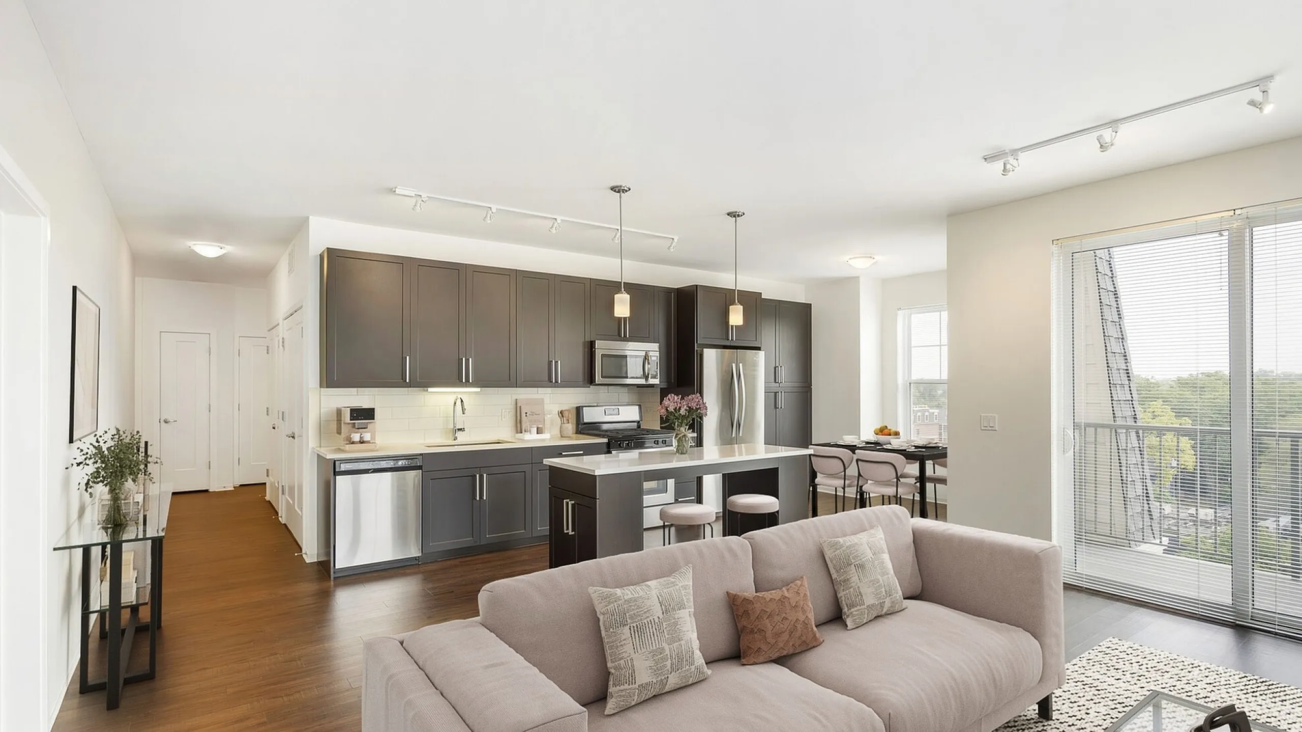 Modern kitchen with sleek dark cabinets, stainless steel appliances, and an inviting island, filled with natural light from large windows overlooking a lush view.