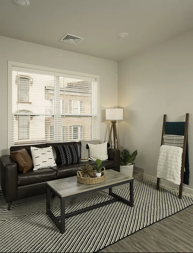 Charming modern apartment living room with cozy decor, large window for natural light, and a glimpse into an inviting bedroom.