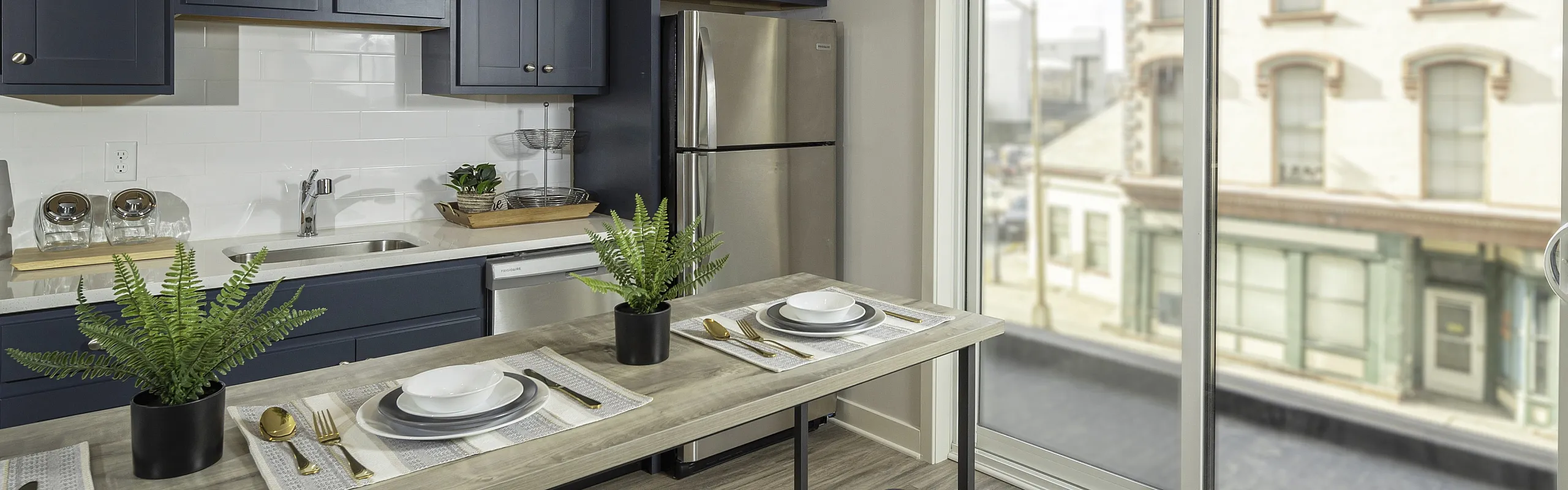 Bright, modern kitchen with sleek blue cabinets and a spacious dining area overlooking a charming street view.