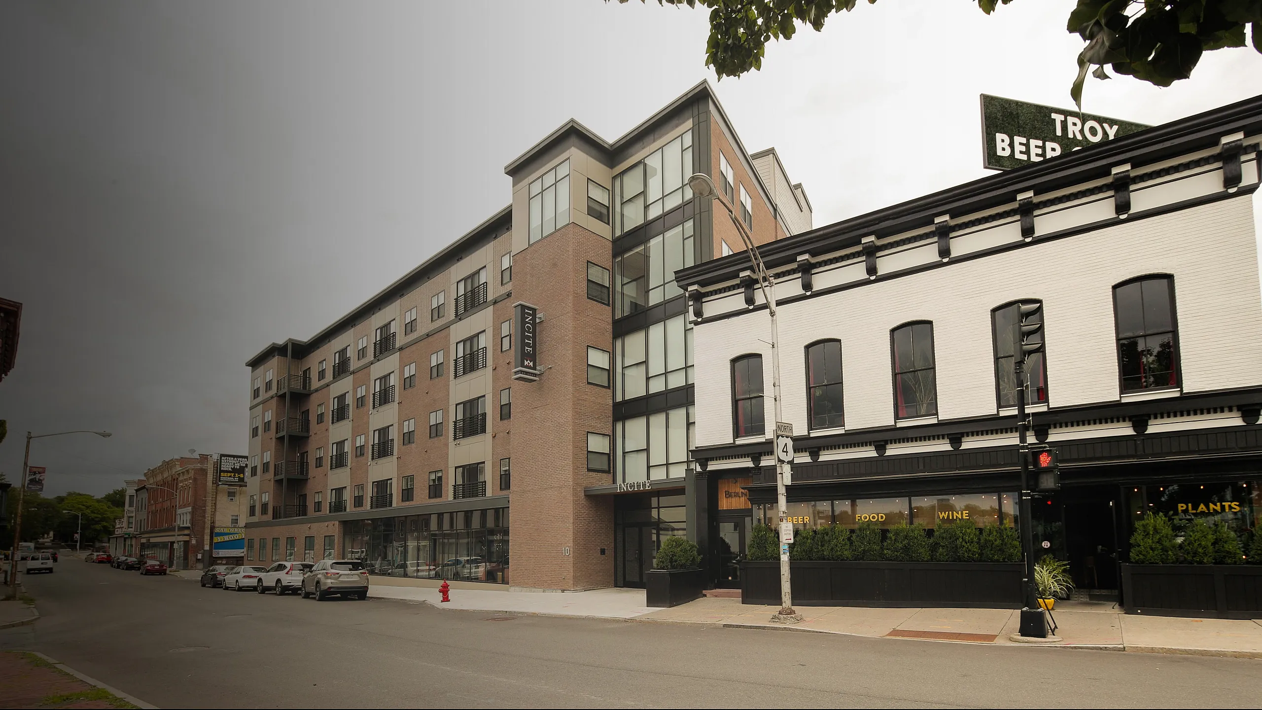 Modern urban apartment building with large windows and street-level shops, ideal for city living.