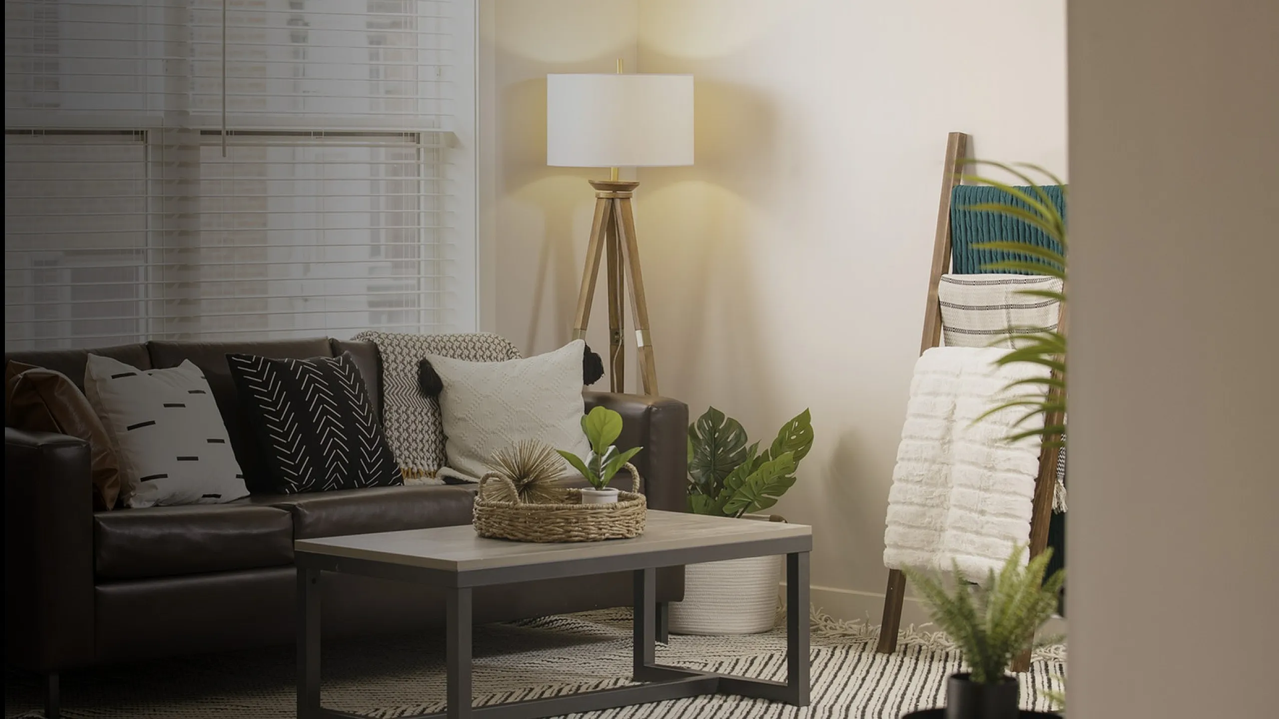 Inviting modern living room with stylish leather sofa, cozy pillows, chic floor lamp, and lush greenery for a serene, homey atmosphere.