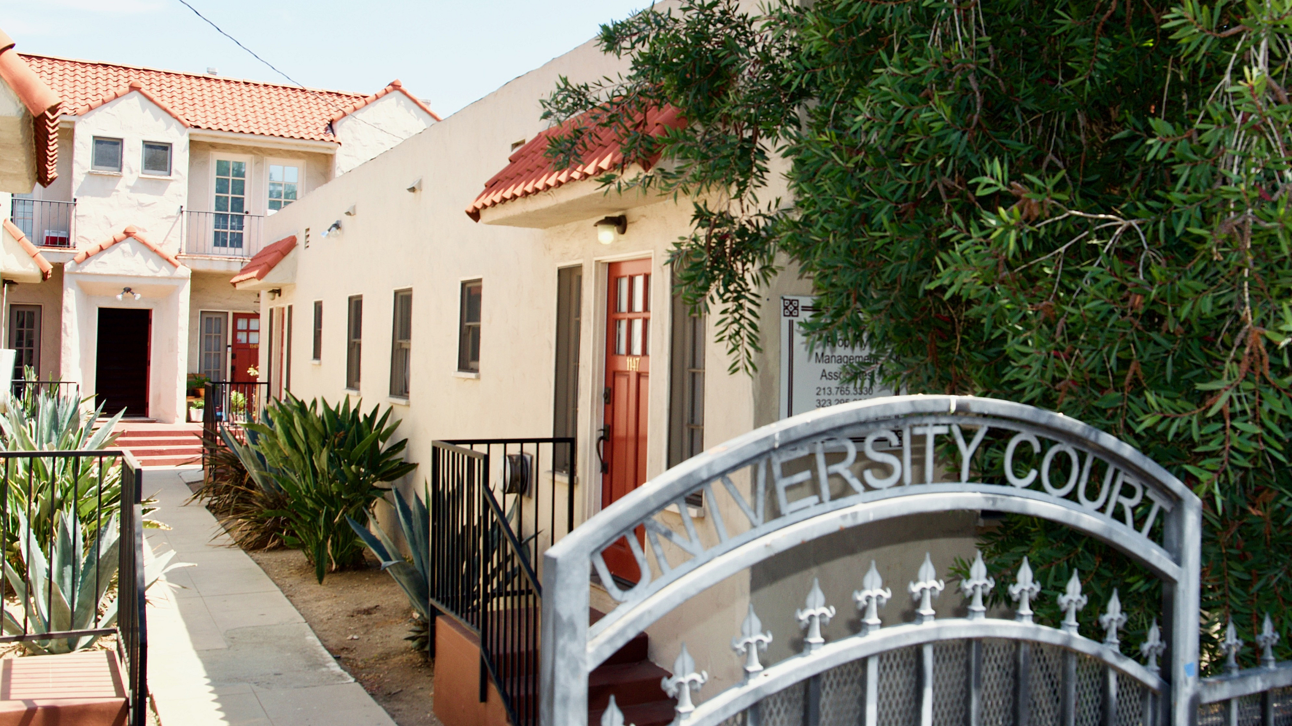 Charming apartment complex with Spanish-style architecture, red tile roofs, and vibrant landscaping at University Court.